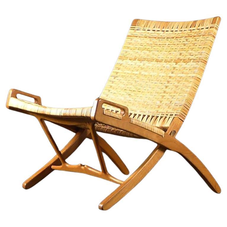 Hans J Wegner (1914-2007), Folding Lounge Chair, model JH-512, original design 1949, this example possibly produced circa 1960.  

Produced by Johannes Hansen, Copenhagen Denmark, and bearing stamped marks (see images).

The folding oak frame has