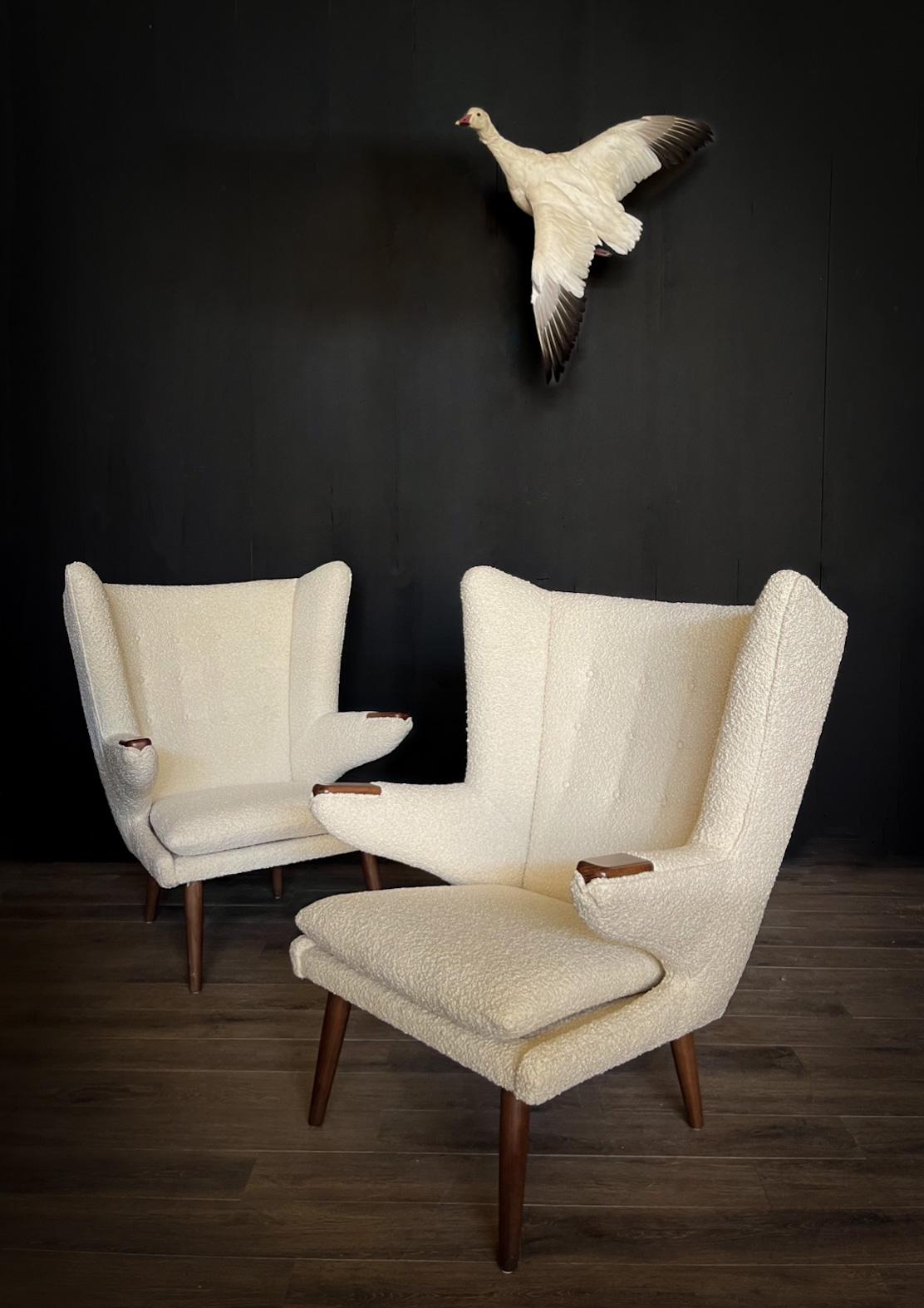 Verschönern Sie Ihren Raum mit diesem außergewöhnlichen Angebot: ein fesselndes Paar Stühle im Vintage Papa-Bär-Stil, die an das zeitlose Modell AP 19 von Hans J. Wegner erinnern, begleitet von einer wunderbar passenden Ottomane. Diese Stühle sind