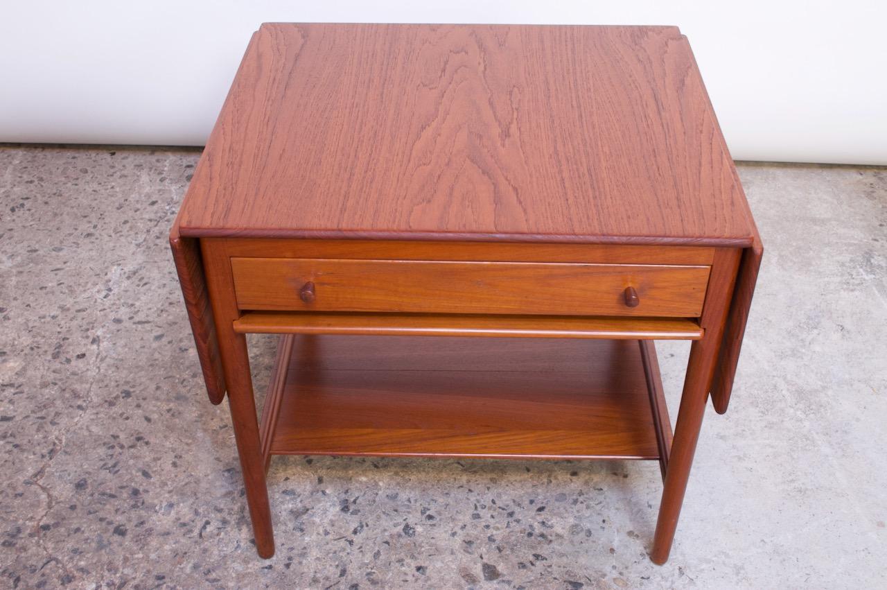 1950s Danish solid teak sewing or side table (model AT33) designed by Hans J Wegner and manufactured Andreas Tuck. Crafted with two drop leaves that extend the table from 26.25