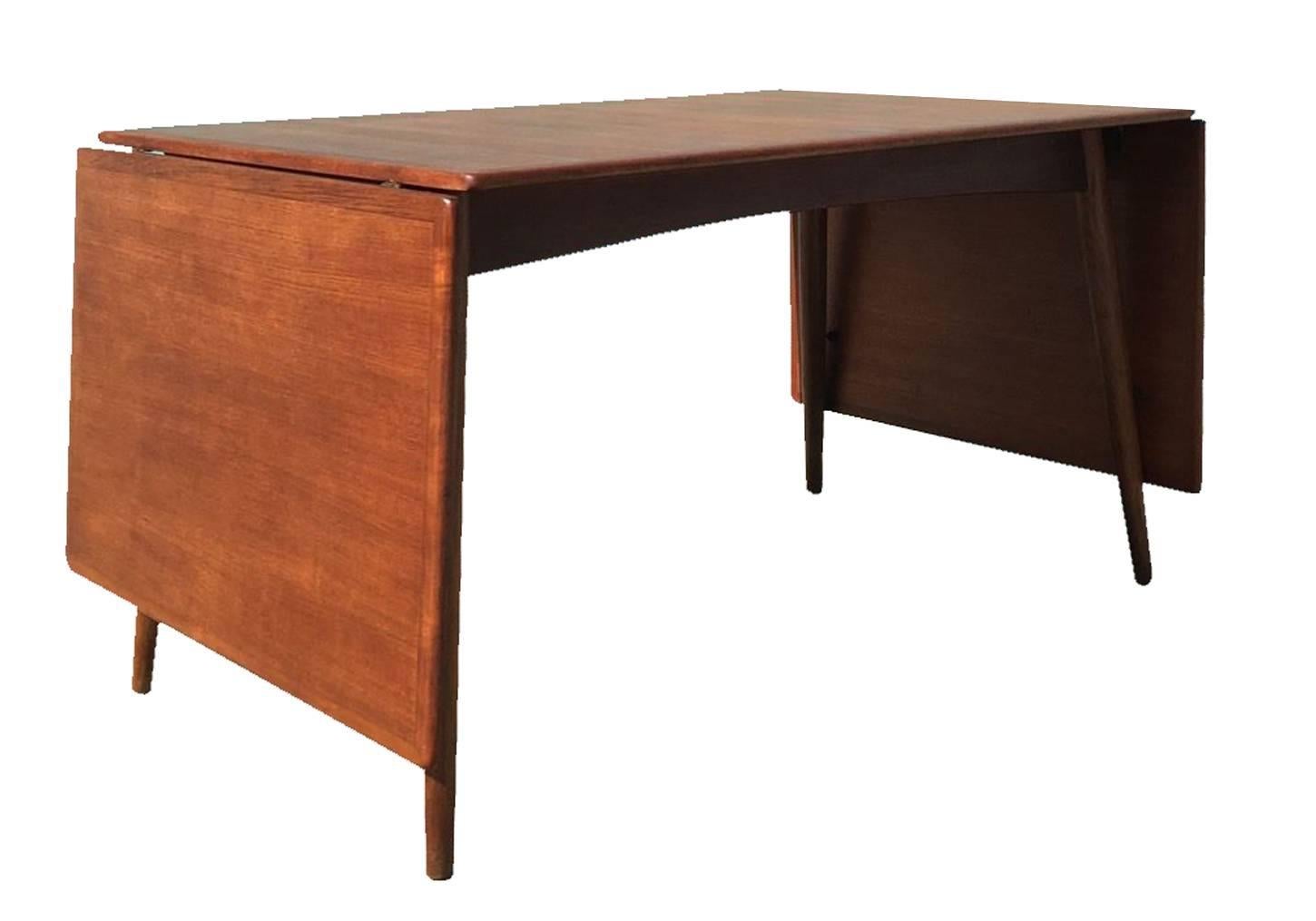 Danish modern teak dining table designed by Hans Wegner for Andreas Tuck in very good vintage condition, circa 1960. Drop leaves can be easily removed or raised to enlarge size. Oak wood splayed legs and accents with teak wood top.