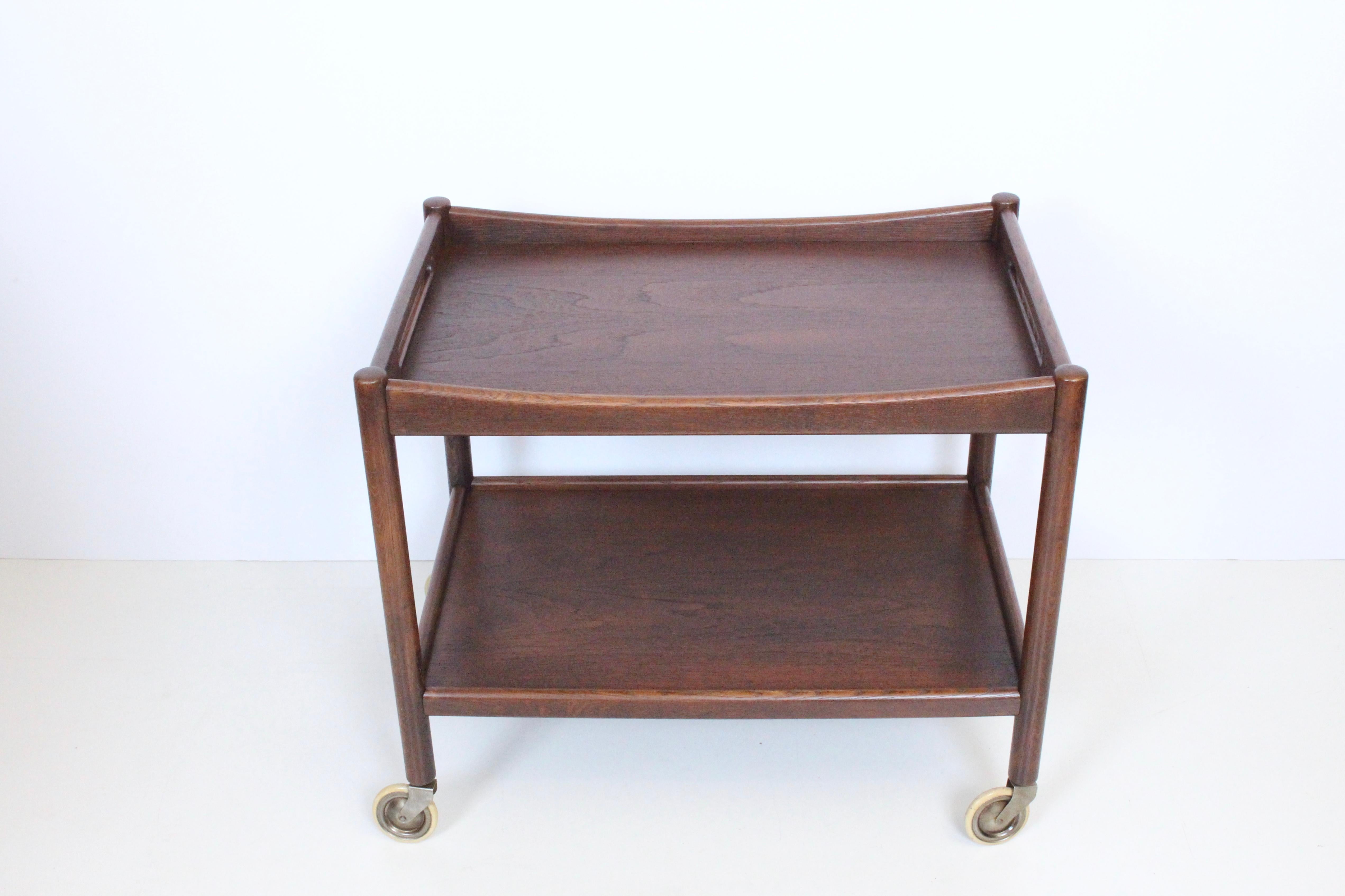 Hans Wegner for Andreas tuck rolling teak trolley, bar cart, tea cart, serving cart. Featuring an all teak rectangular lipped and handle Teak Tray with lipped lower shelf and original rubber tread to casters. Sturdy. Classic. Danish Modern. Stamped