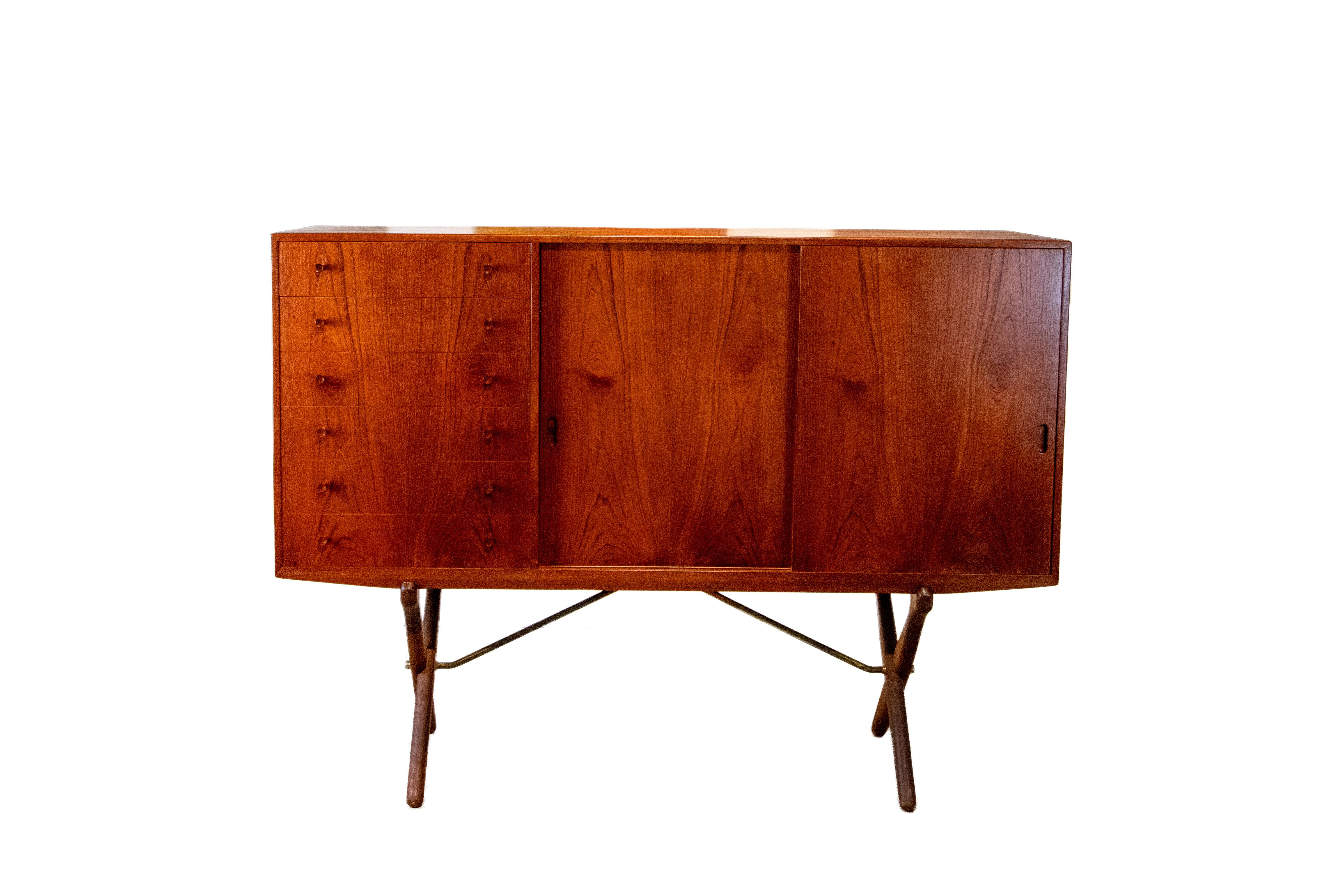 A tall sideboard, model CH304, designed by Hans Wegner for Carl Hansen. Teak cabinet with three distinct sections. The left side having veneer matched drawers, sliding doors canceling open shelving in the middle, and 5 pullout trays on the right.