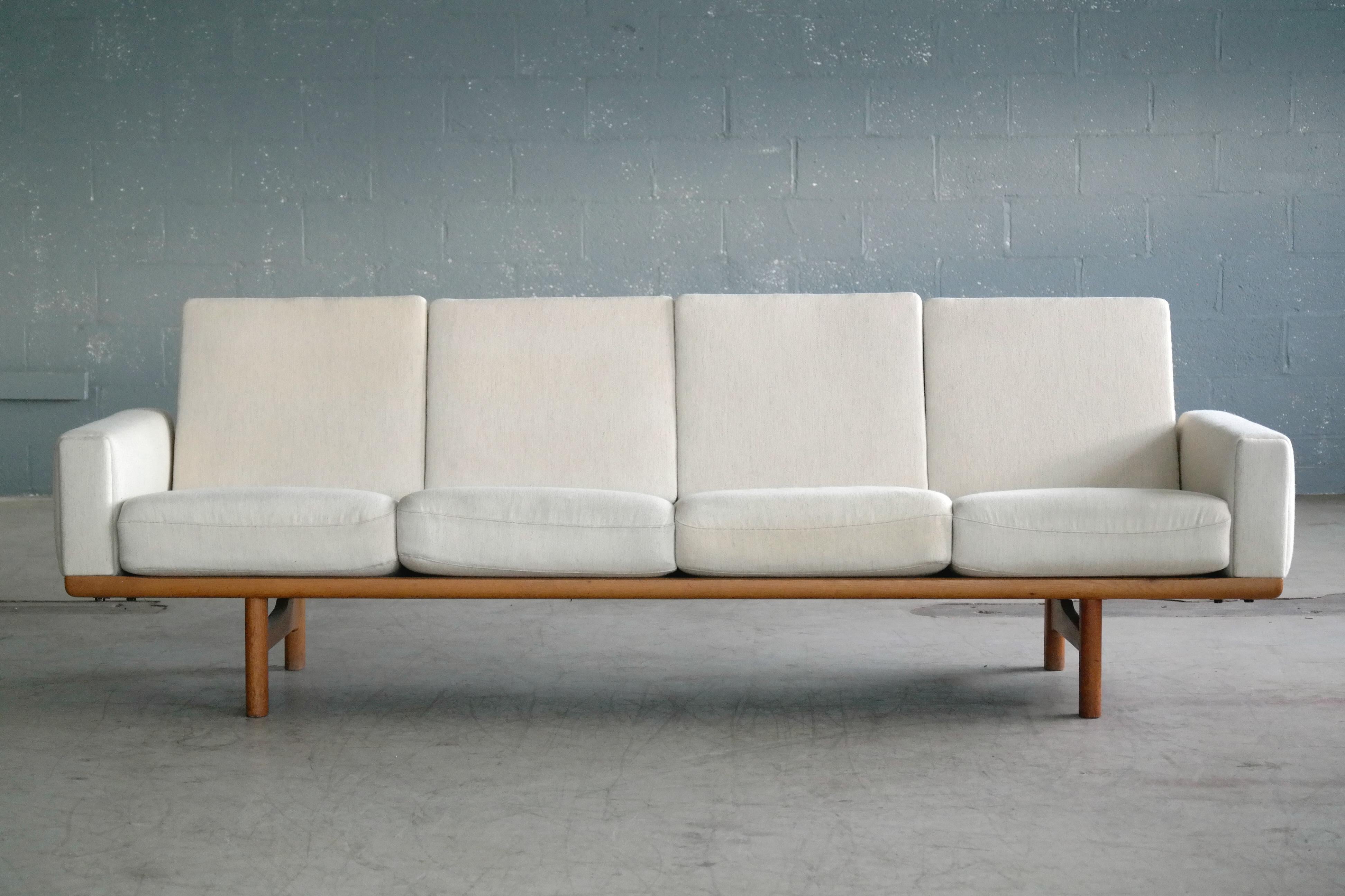 Beautiful Hans Wegner four seat sofa model GE236/4 designed by Wegner for GETAMA in 1955 and likely manufactured sometime in the late 1960s. The sofa has a solid oak frame with arm rests and cushions in the original light beige wool fabric by