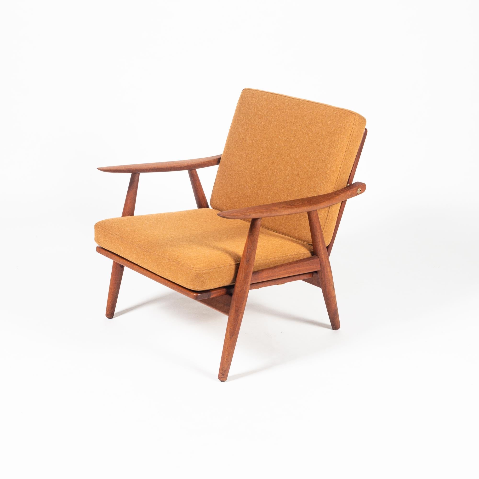 Hans Wegner GE-270 lounge chair in solid teak and newly upholstered in Dry Sunflower Canadian wool, circa 1950s. This lounge chair has a sculpted solid teak frame with exposed, bespoke brass fittings. Unlike the Wegner Cigar Series or other lounge