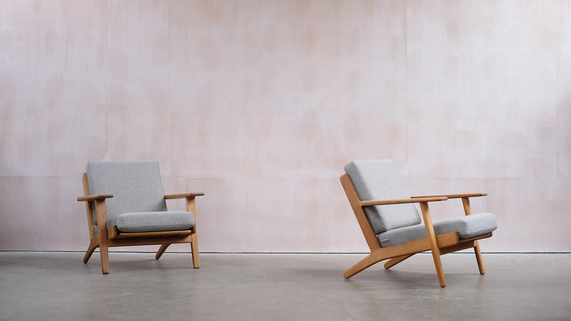 Fantastic pair of GE290 lounge chairs designed by Hans Wegner for Getama, Denmark. Solid oak frames with wonderful grain pattern and original patina. Original sprung cushions, fully reconditioned and recovered with a neutral grey fabric by Camira.