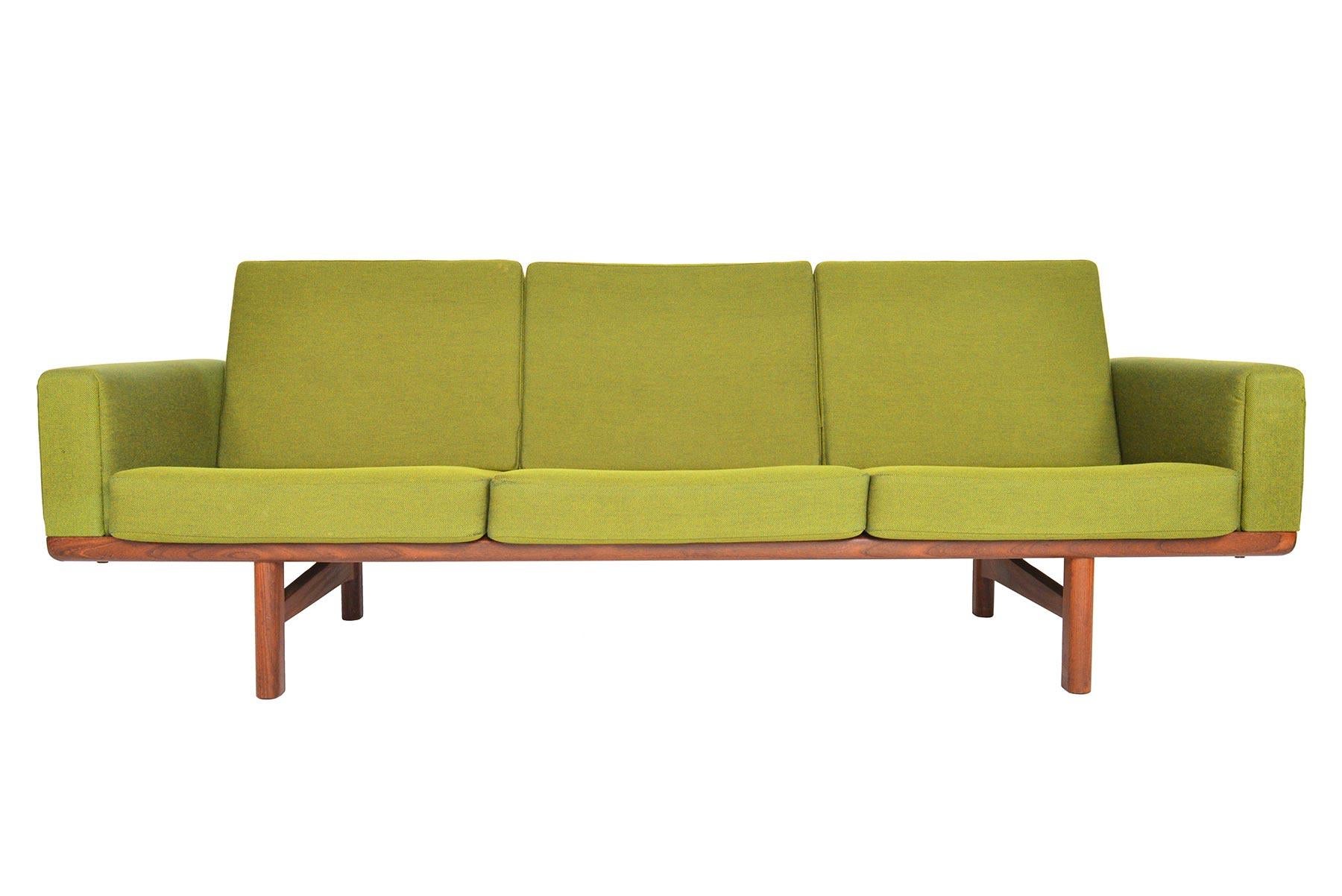 This Danish modern three-seat sofa in walnut was designed by Hans Wegner as model GE- 236-3 for GETAMA in the 1950s. This excellently preserved piece showcases a sculptural back while providing upholstered arms and six original sprung cushions.