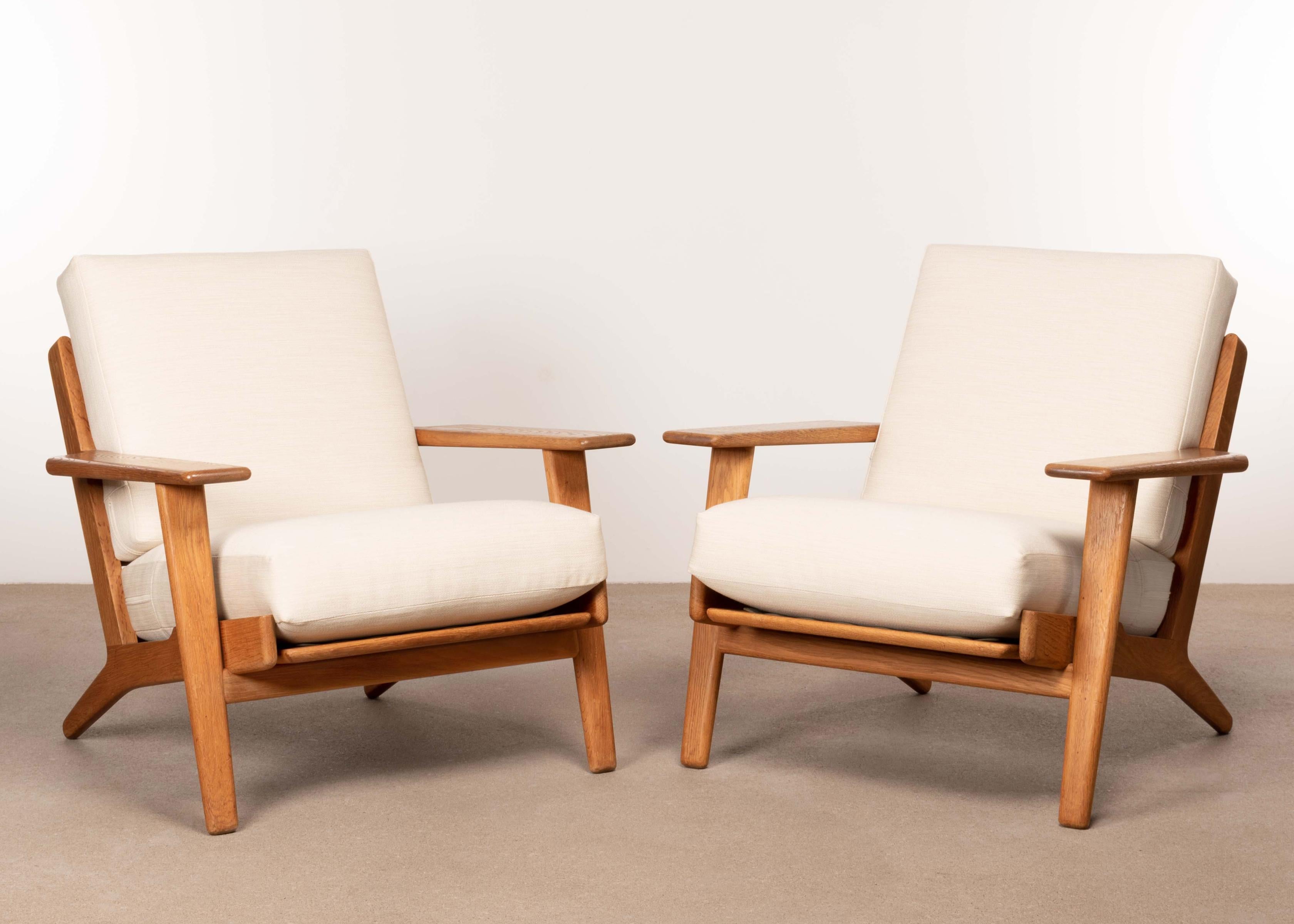 Great pair of Hans Hans Wegner GE290 easy / lounge chairs for GETAMA. Solid oak frames with strong wood grain. Original spring cushions reupholstered with Kvadrat Raf Simons Balder wool (0212) with a nice soft texture to that increases comfort and
