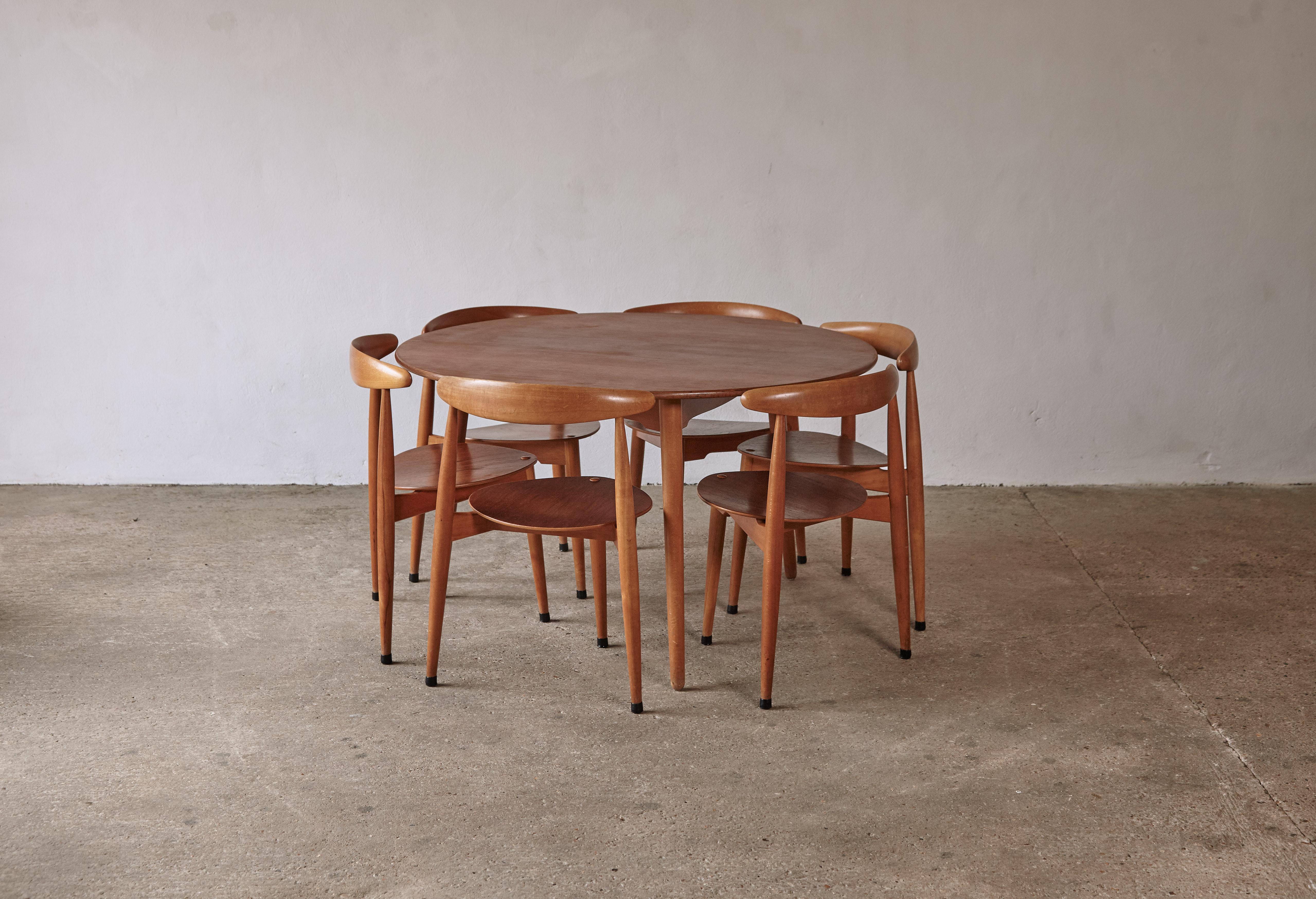 A rarely found Heart dining set designed in the early 50’s by Hans Wegner and produced by Fritz Hansen, Denmark. Six three legged beech and teak chairs and matching round table. Feint makers mark to the underside of each chair and the table. Very