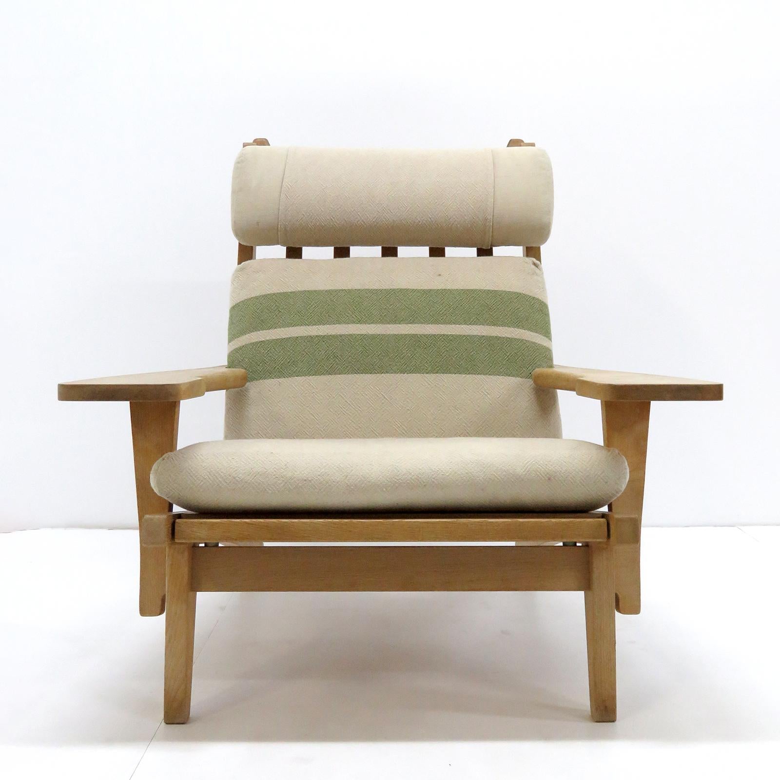 Large-scale high back armchair by Hans Wegner with solid oak frame and original cushions in beige/greenish striped wool, produced by GETAMA in 1969, model GE 375, detachable neck cushion, original makers mark to underside.