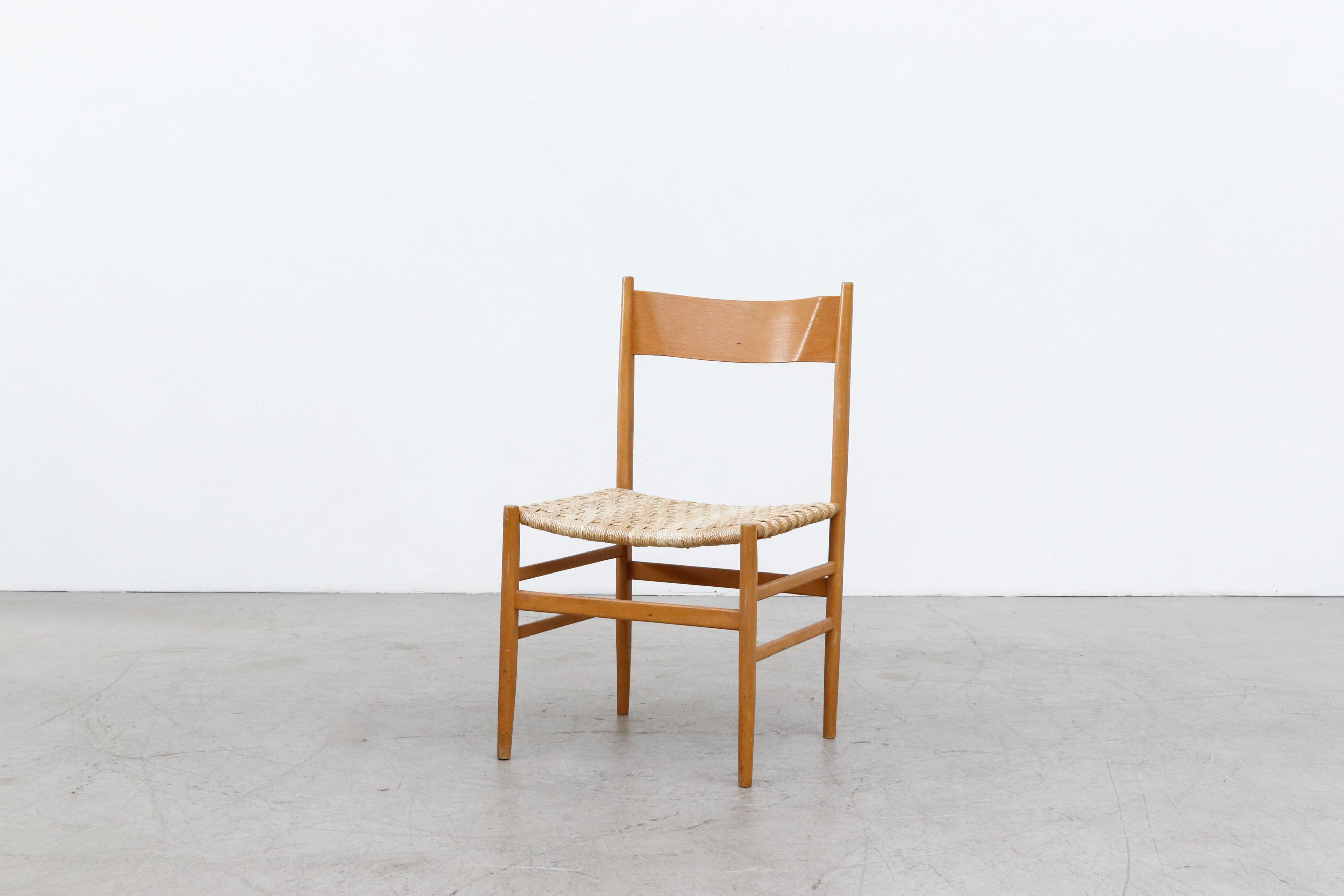 Hans Wegner inspired Danish dining chairs with woven synthetic rope seats and blonde wood frames from a Dutch church. Chairs are in original condition with visible wear and patina to the frames and seating, including some discoloration and fading to