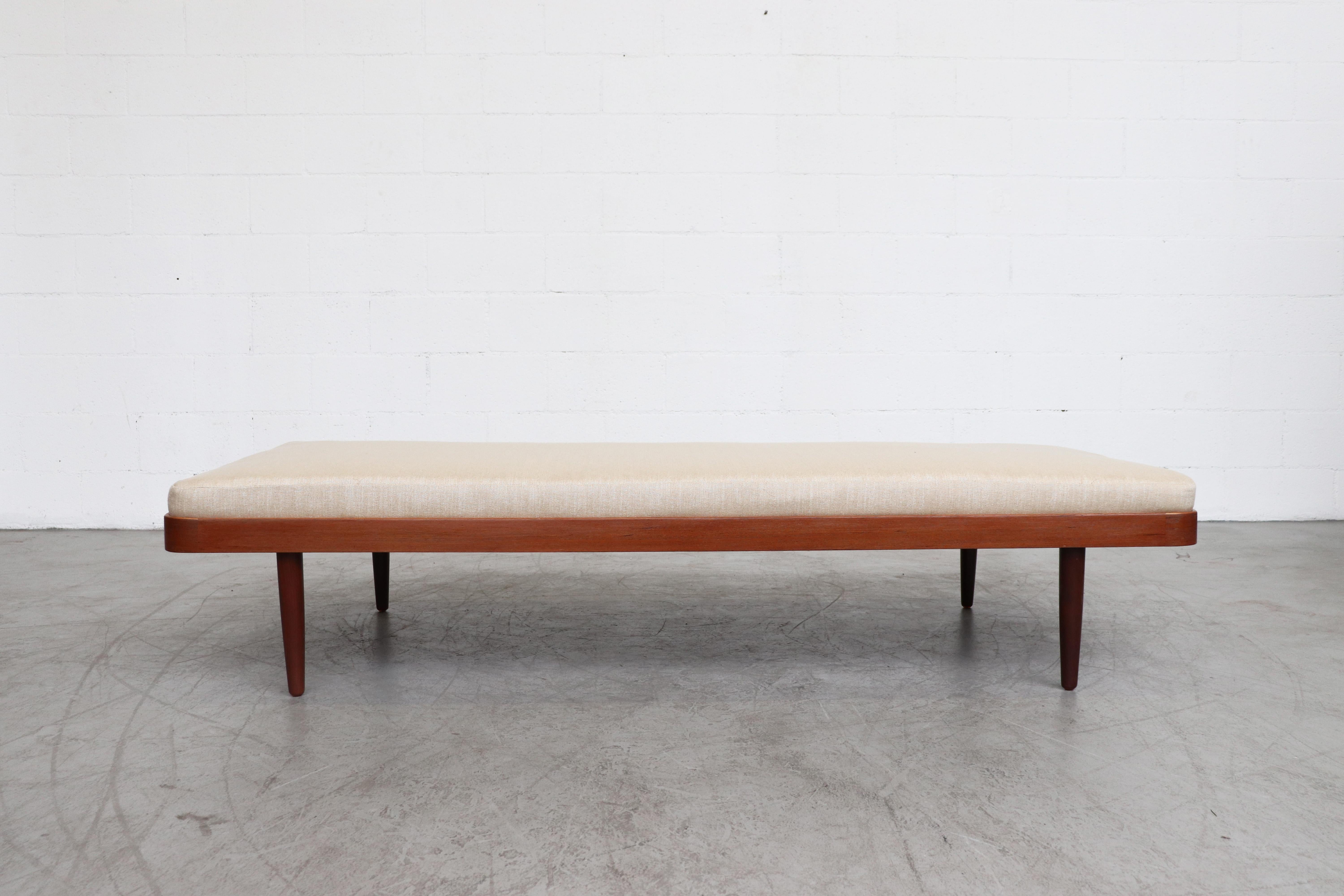 Midcentury lightly refinished teak daybed with rounded edges and newly made and upholstered bone white mattress and tapered teak legs. Frame in good original condition with some signs of wear.
