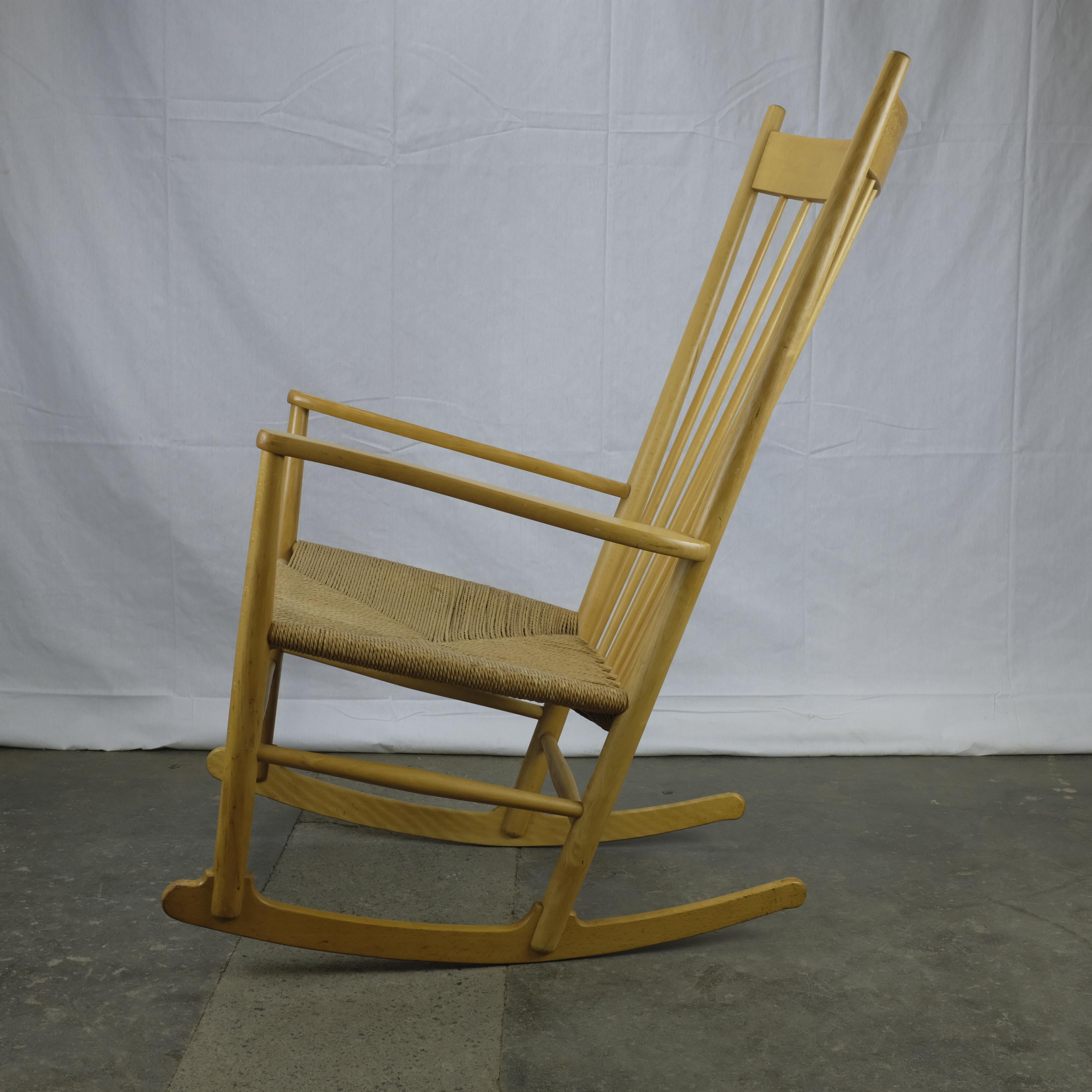 Model J16 rocking chair with solid beech frame and paper cord seat. 

The J16 was designed in 1944 by Hans Wegner and this example was made in 1979 by FDB Møbler. Stamp with manufacturing date on the underside of the right armrest and foil sticker