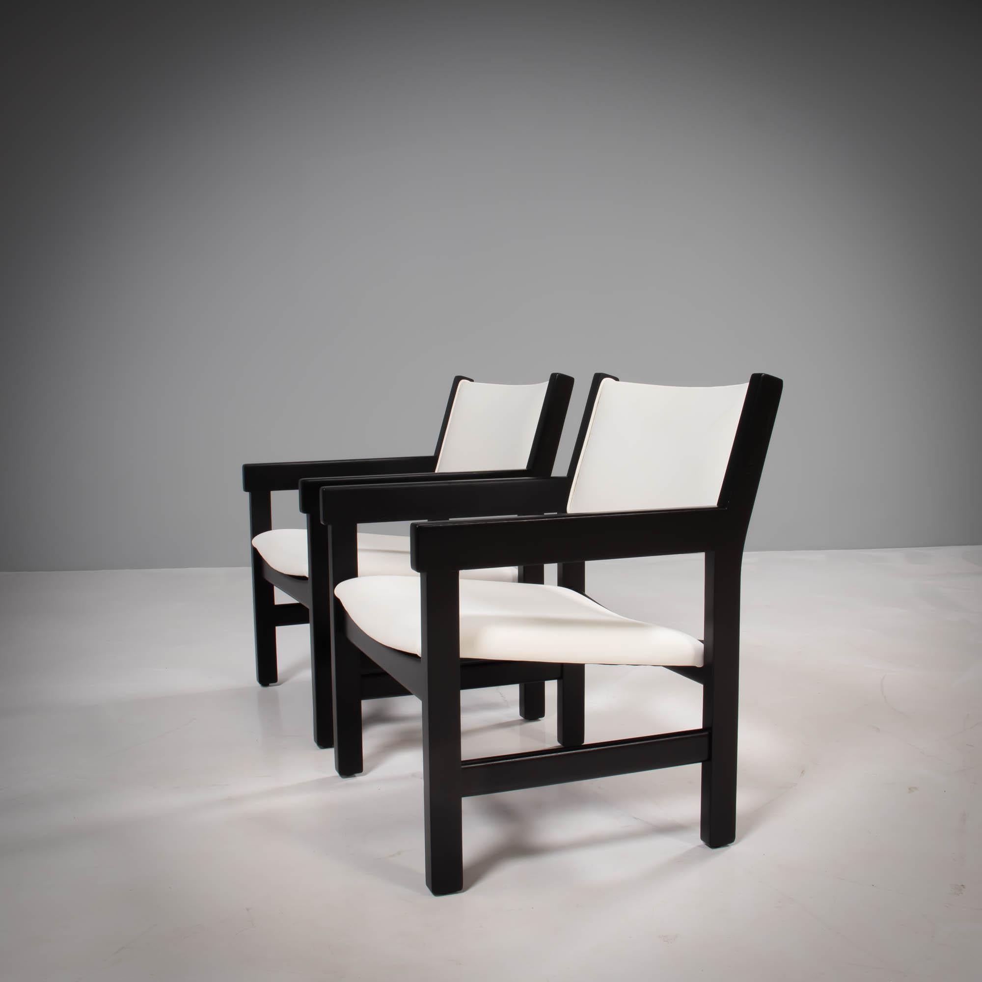 Designed by Hans J. Wegner for GETAMA, this set of GE 151 armchairs are a Classic example of Mid-Century Modern design.

Featuring angular black painted beechwood frames and arms, the newly restored chairs have padded seats and backrests which