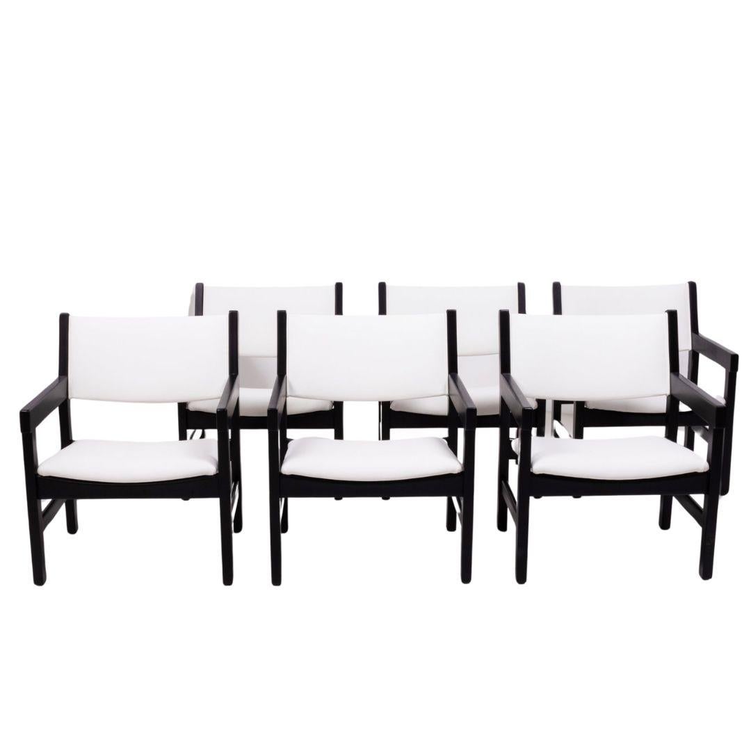 Designed by Hans J. Wegner for GETAMA, this set of six GE 151 chairs are a Classic example of Mid-Century Modern design.

Featuring angular black painted beechwood frames and arms, the newly restored chairs have padded seats and backrests which have