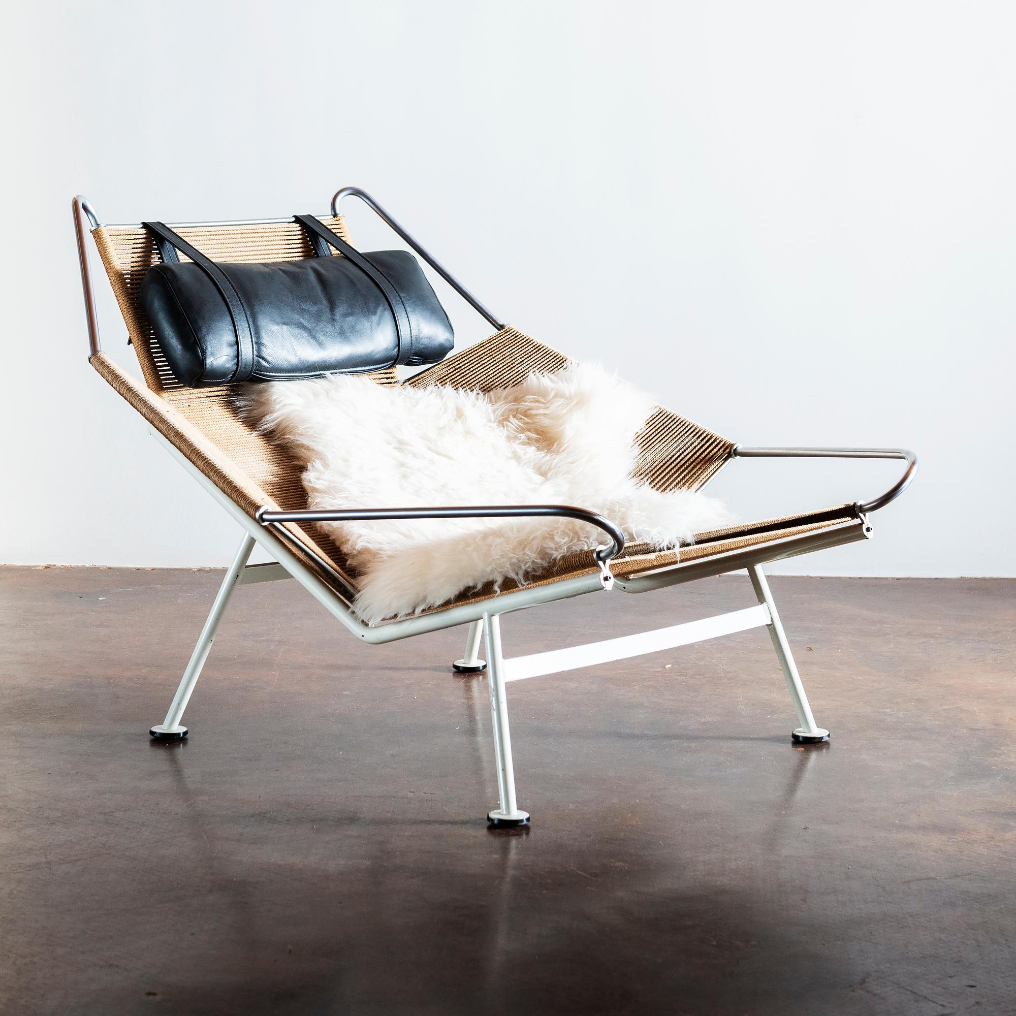 Early Hans Wegner Flag Halyard chair with original lacquered steel frame in white with black feet. Seat and back of continuous plaited flag halyard. Includes adjustable black leather headrest and sheepskin throw. Model GE 225 was designed in 1950