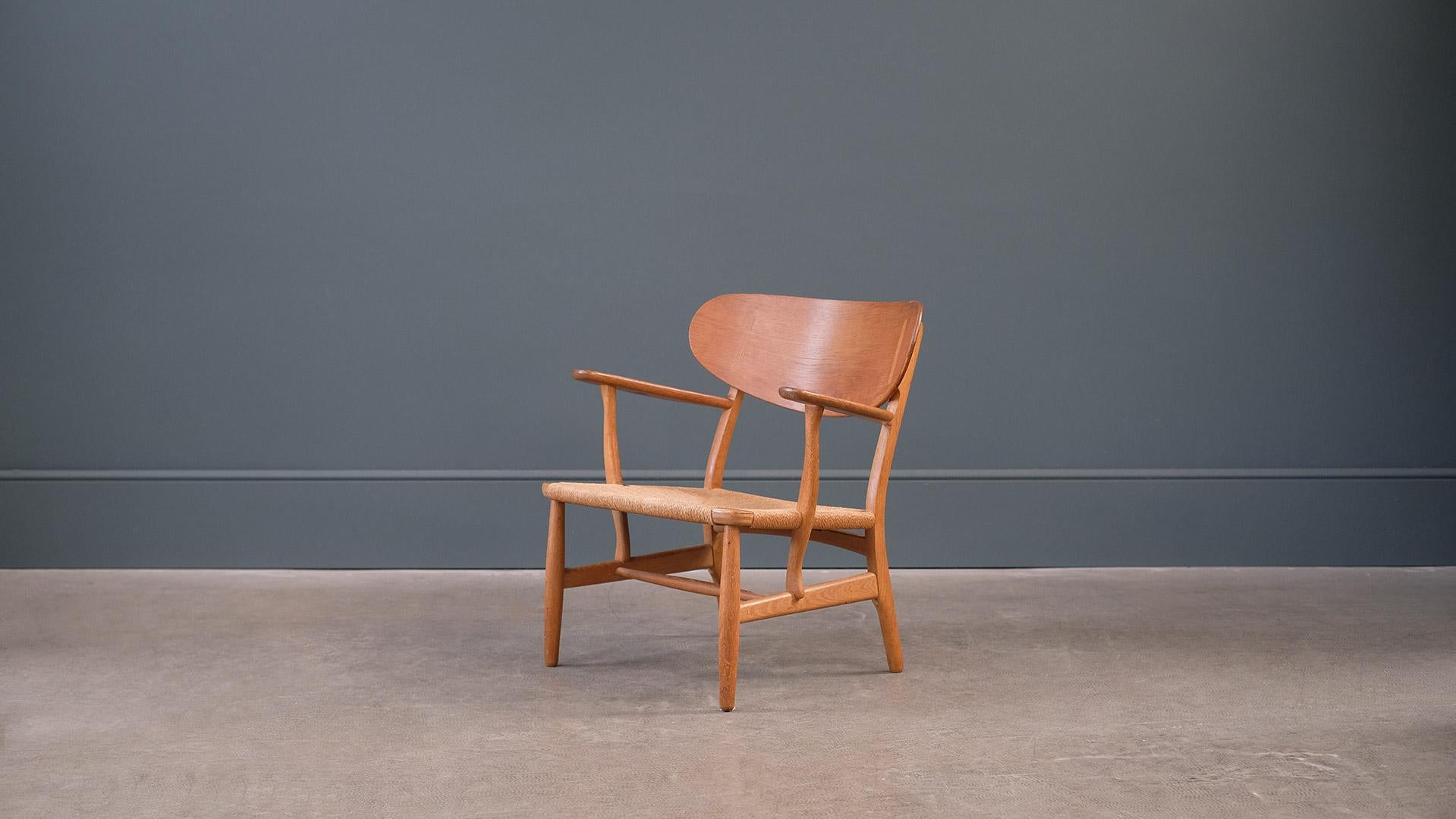 Original CH22 lounge chair in solid oak with papercord seat designed by Hans Wegner for Carl Hansen, Denmark. Amazing example of this beautiful lounge chair with very striking grain and superb exposed joint detail. Great piece.