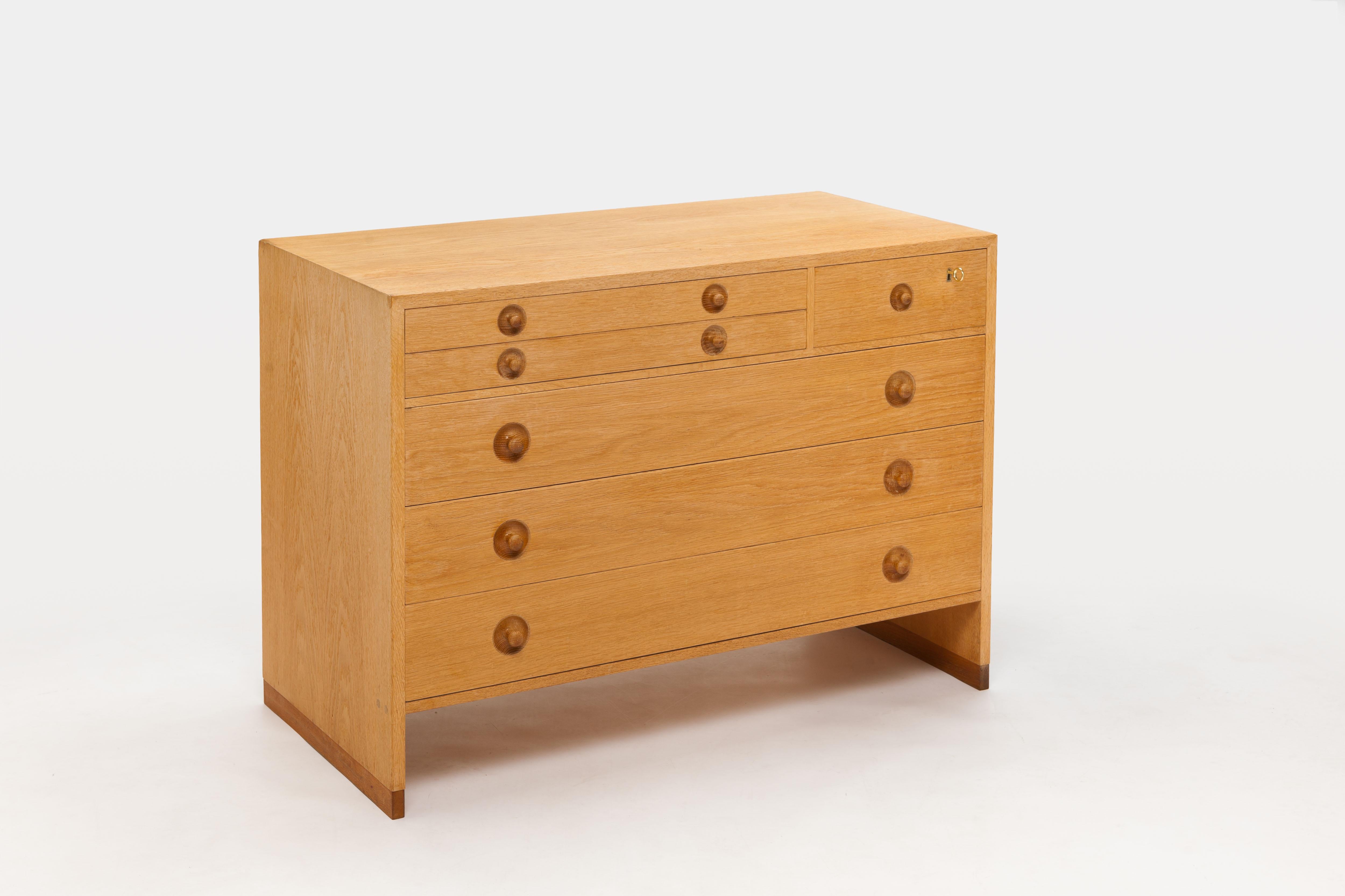 Oak chest of drawers model 16 with characteristic signature solid wooden pull's by Hans Wegner. 
The cabinet is equipped with different sizes of drawers, the top drawer of which is executed with original green felt. The other drawers are made of