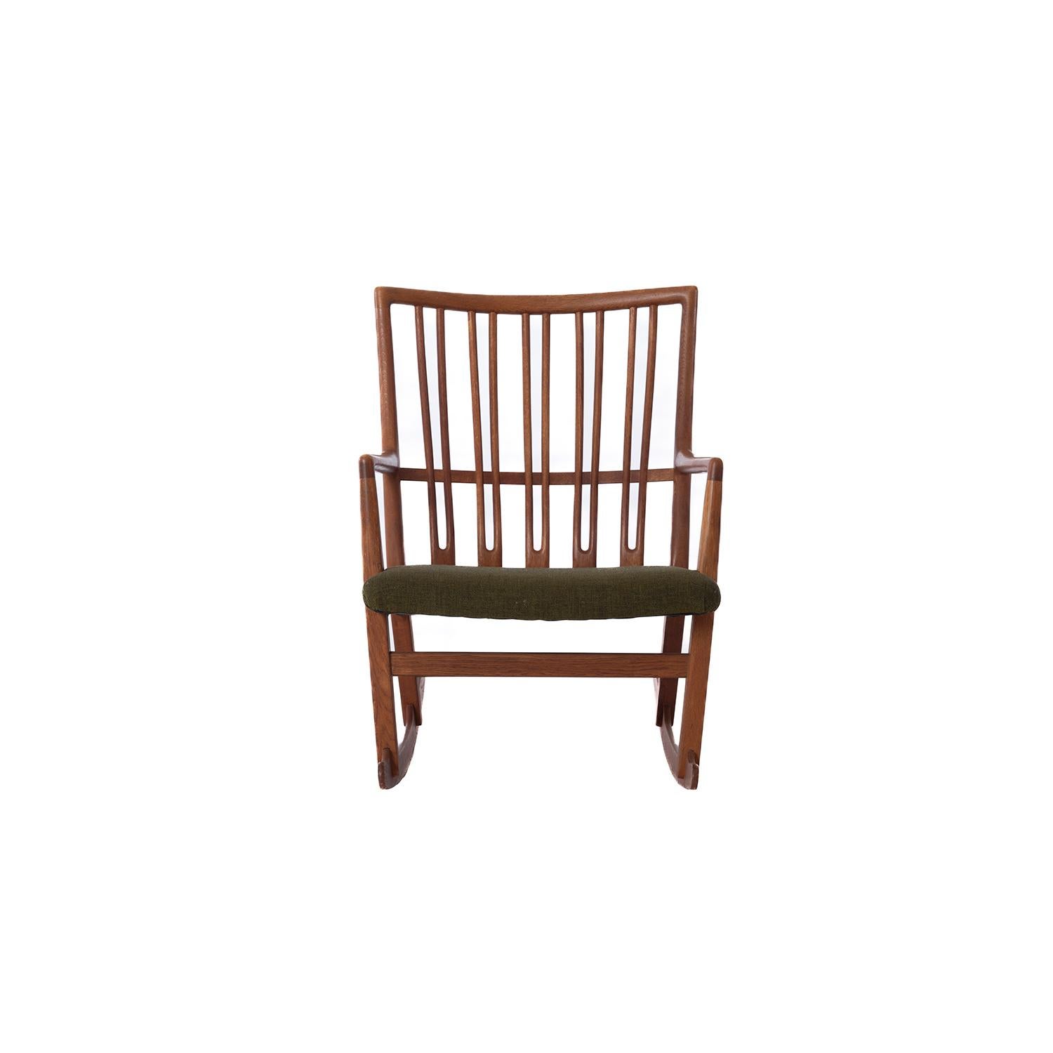 A hard to find Hans J. Wegner designed Oak rocking chair produced by Mikael Laursen. An early rocker design by famed Danish architect. Oak has a rich patina. Upholstered in a green wool. 

Professional, skilled furniture restoration is an integral