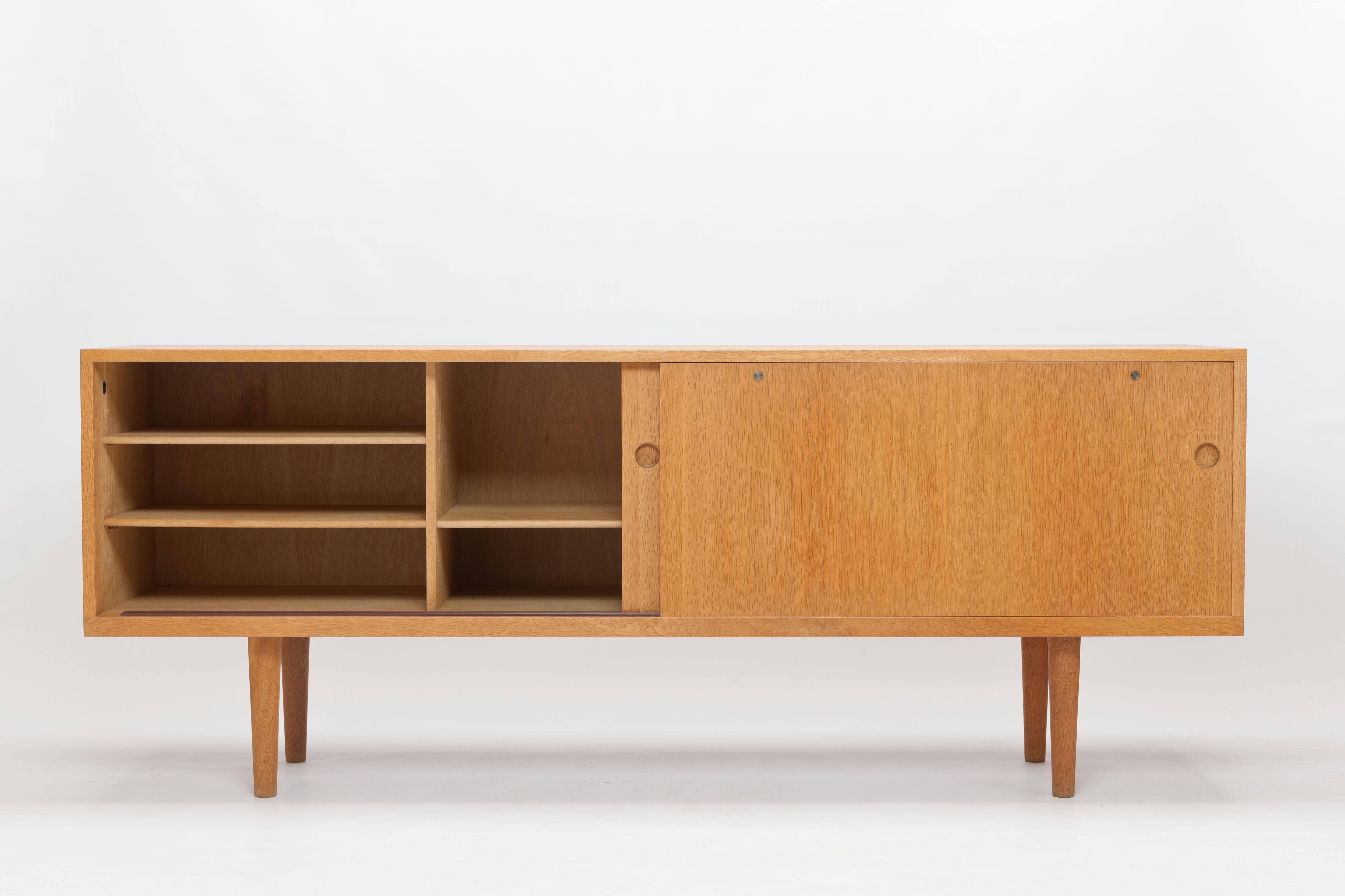This sideboard, model RY26, is a wonderful example of a characteristic Hans j. Wegner design: a sober timeless and understated functional design of exceptionally high quality. 

The cabinet is made of oak, mainly solid wood, with the only