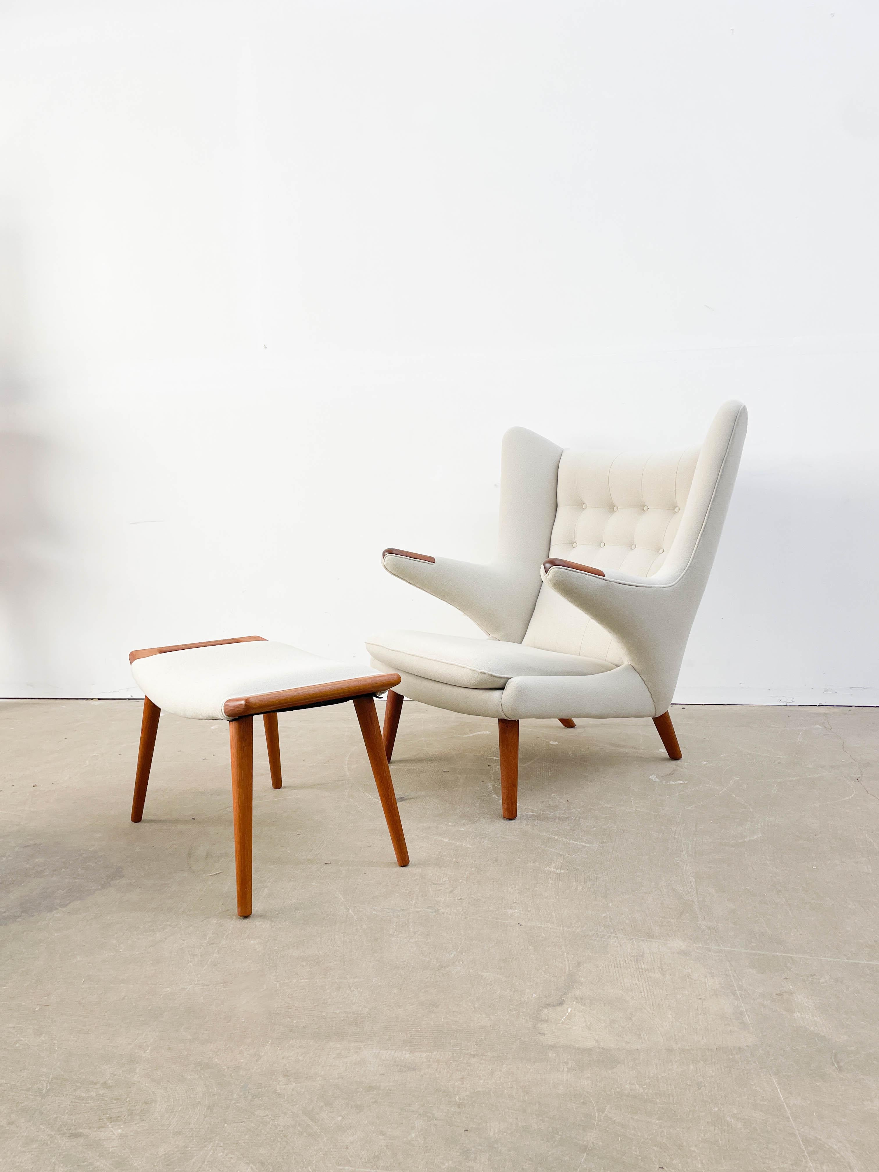 Hans Wegner's AP19 'Papa Bear' chair and ottoman. Designed in 1953 and prized for its superb comfort and striking form. This example was reupholstered in the 1990s in an excellent cream Hallingdal 65 wool. It has teak legs and paws/nails on the end