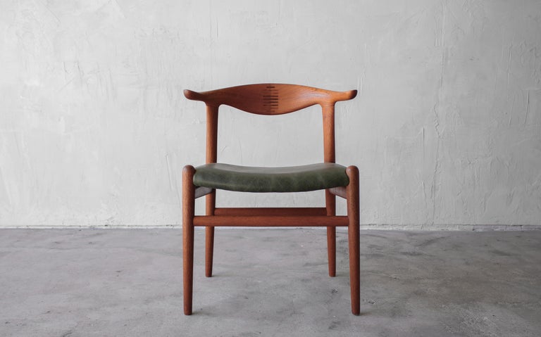 A simple and sophisticated classic, Danish modern beauty, the PP505 Cow Horn chair by Hans J. Wegner for Johannes Hansen. Solid teak with rosewood accents and beautiful aged green leather seat.

Chair is in beautiful vintage condition and has been