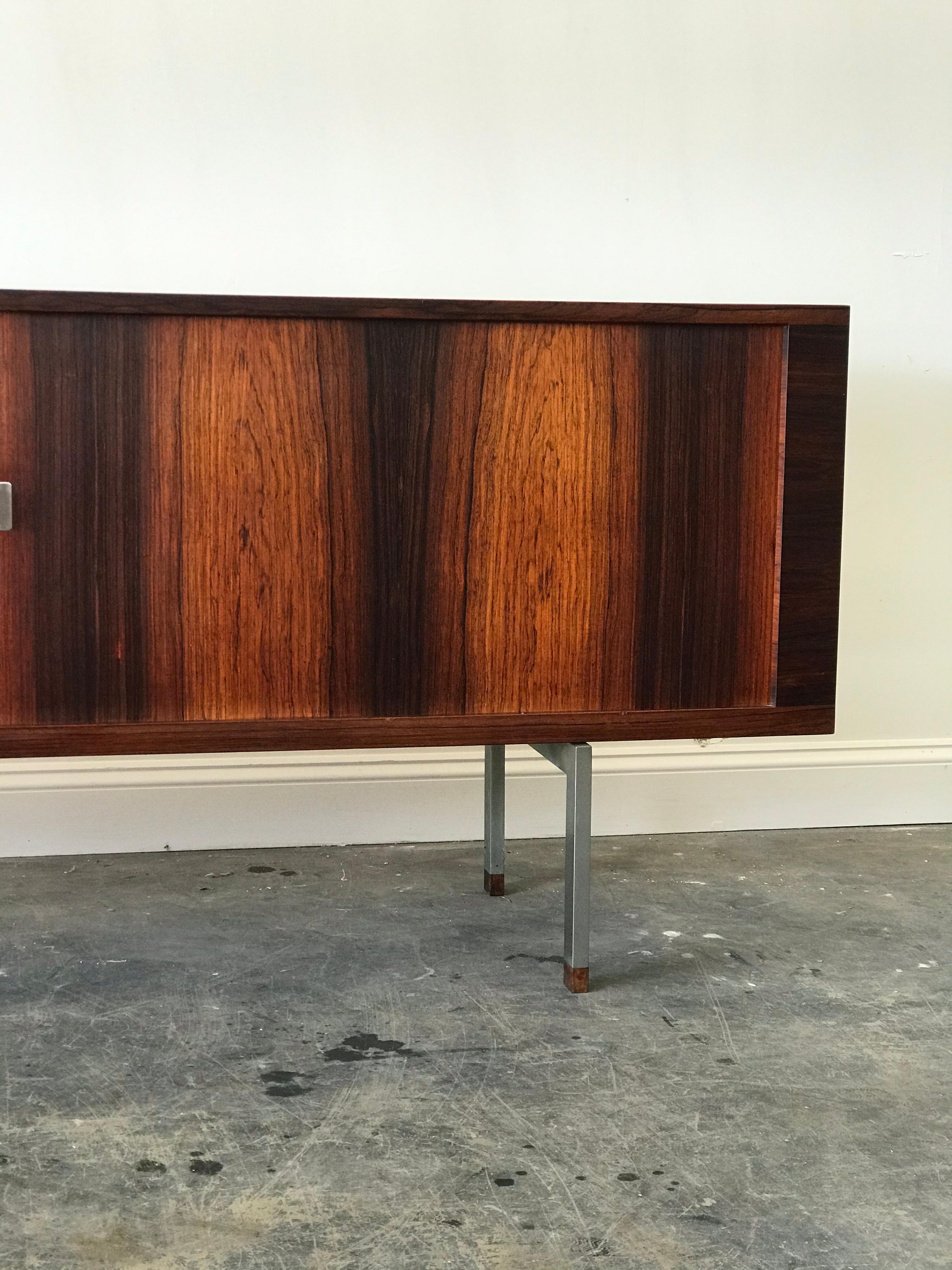 Exquisite rosewood sideboard or credenza by Hans Wegner for Ry Mobler, model RY-25. 

Sideboard features tambour doors with metal plates and rosewood pulls. Metal legs with rosewood accents. Behind the tambour doors feature adjustable shelves on
