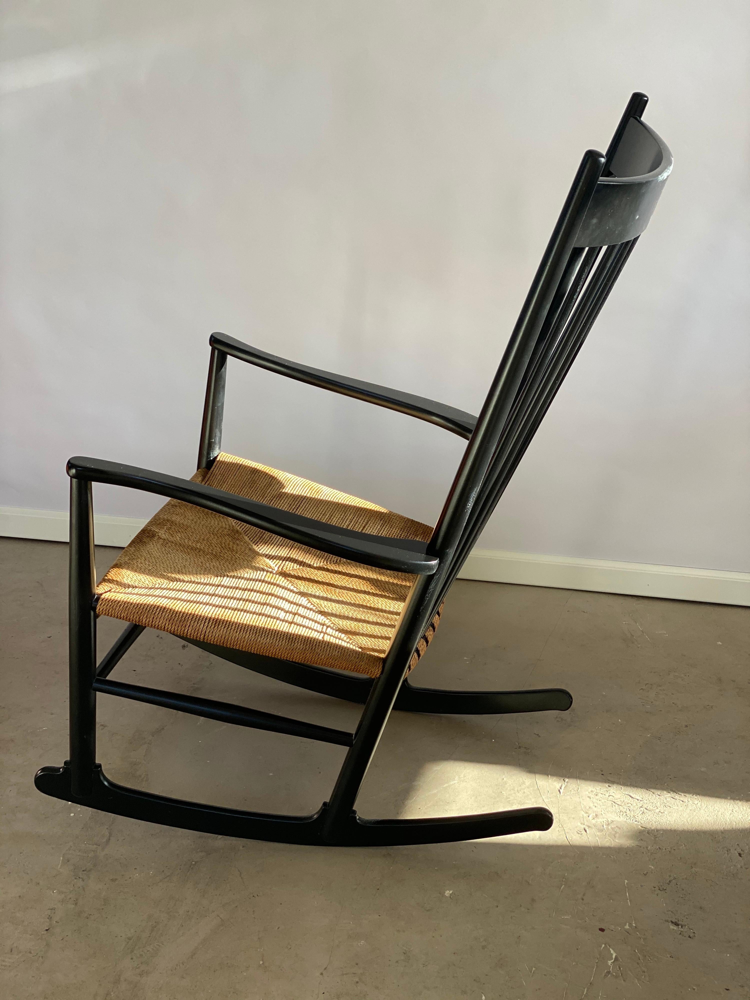 Hans Wegner rocking chair model J.16 with the characteristic high spindle back and the shapely curves lines. This originally black version has been completely overhauled, sanded and professionally re-painted in the original matte black finish. The
