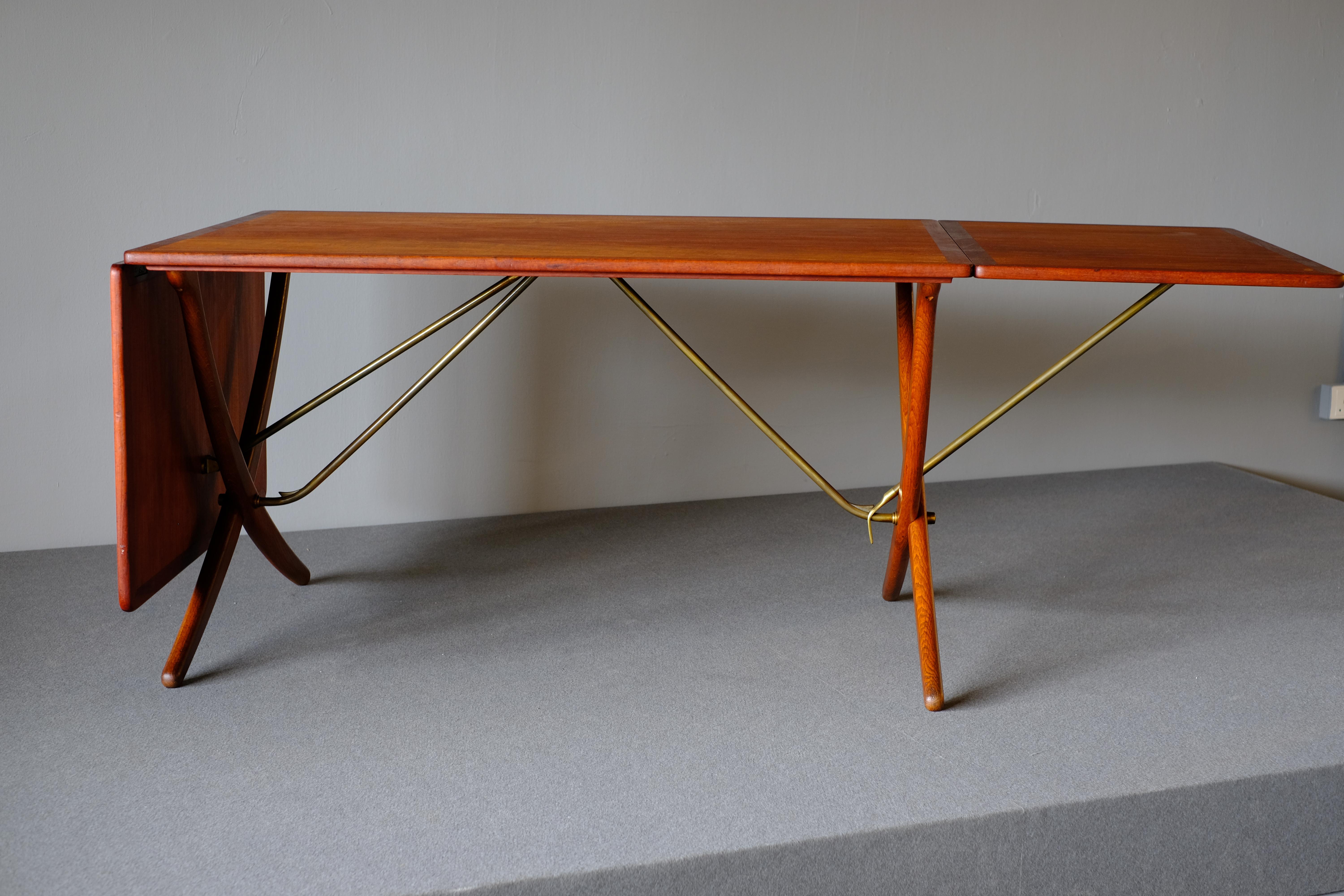 This is a rare teak and oak drop-leaf table. The iconic dining table AT-304 was designed by Hans Wegner and produced by Andreas Tuck. The table is made of teak with two leaves with distinctive the sabre-formed crossed legs in oak which are supported