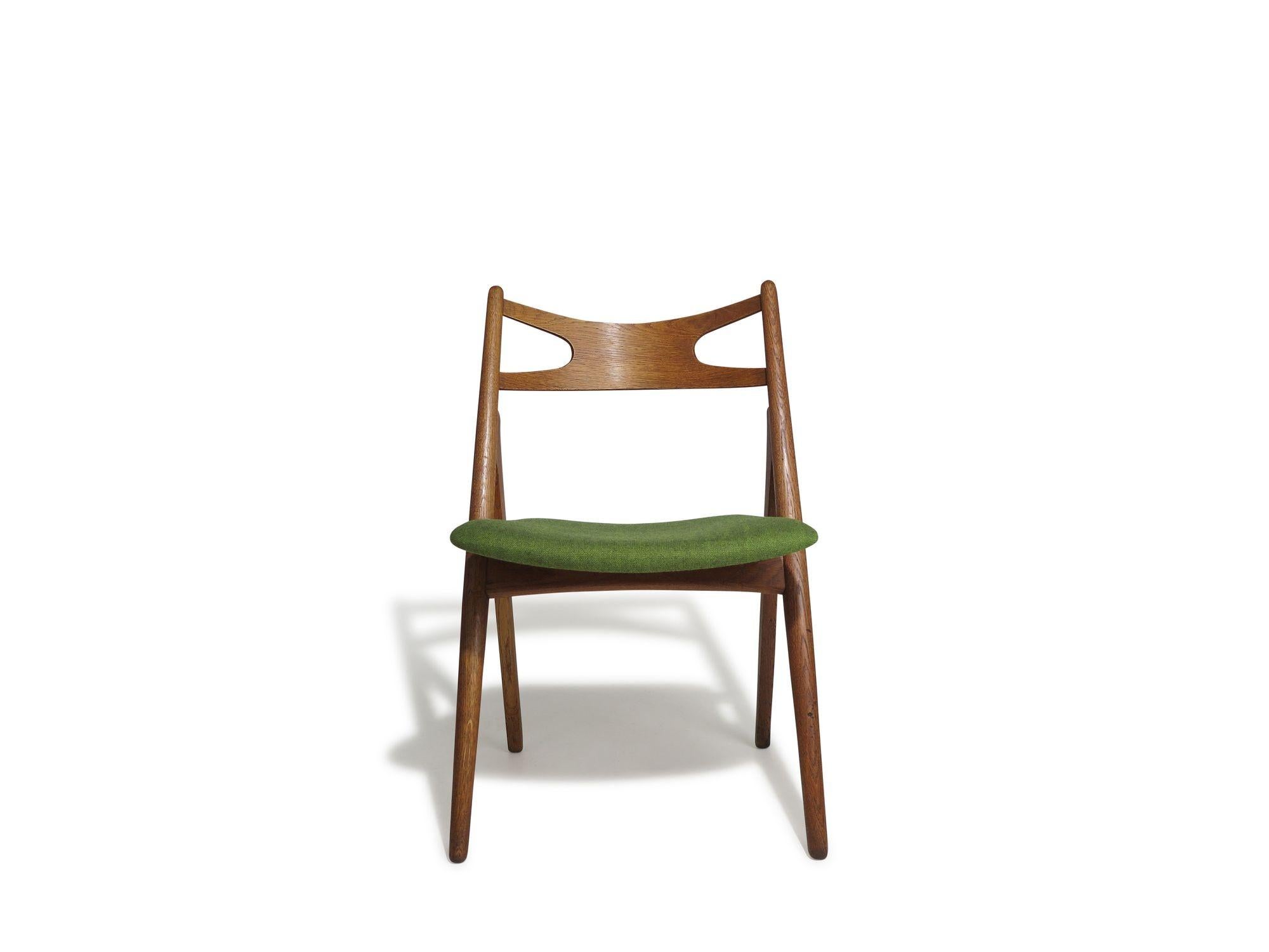 Diseñada en 1952 para Carl Hansen & Søn, la silla de comedor CH29 presenta una estructura en A de roble aceitado con respaldos de teca suavemente curvados y asientos recién tapizados en lana verde. 
Medidas 
Anchura 20,50'' x Profundidad 19'' x