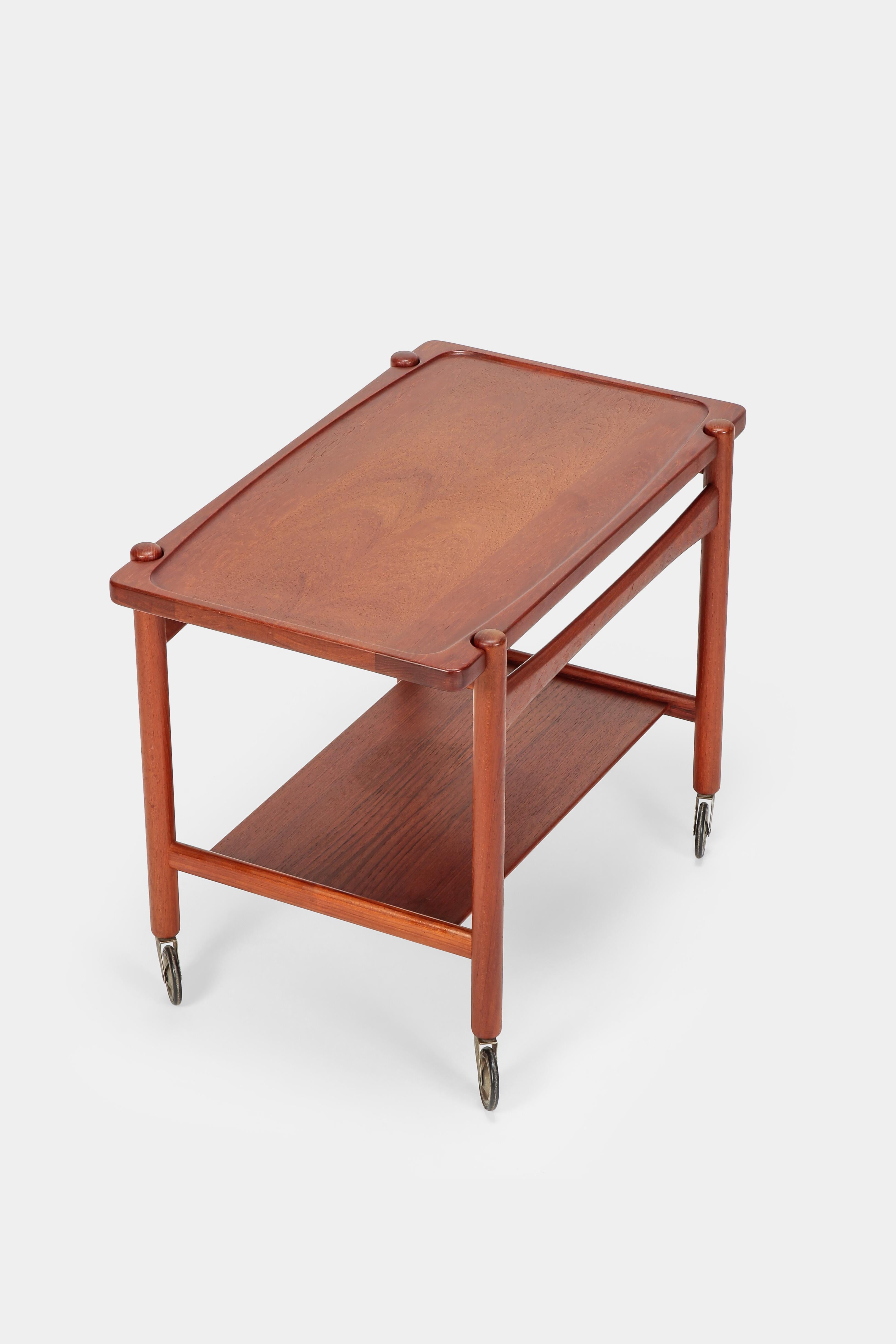 Hans Wegner serving trolley made of solid teak from the sixties, manufactured by Andreas Tuck in Denmark. The tabletop can be taken off and used as a separate serving tray. Vivid color, strong lines softened by curved elements. Adorable object and