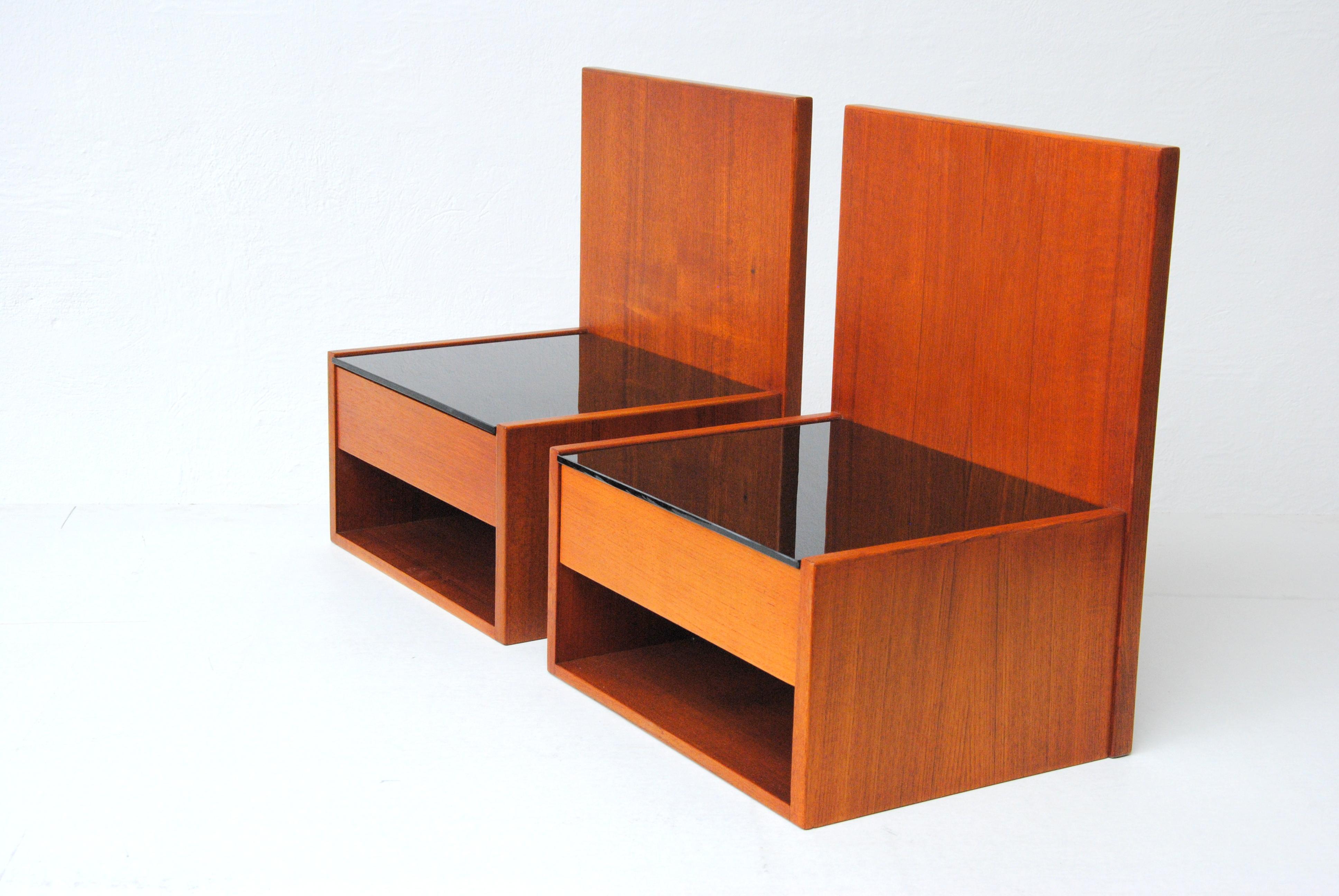 1960's Hans Wegner Set of two floating nightstands in teak and glass by Getama.

The set of floating night stands or shelves in teak, each feature a single drawer with a hidden carved handle, open storage compartment beneath and a black glass table