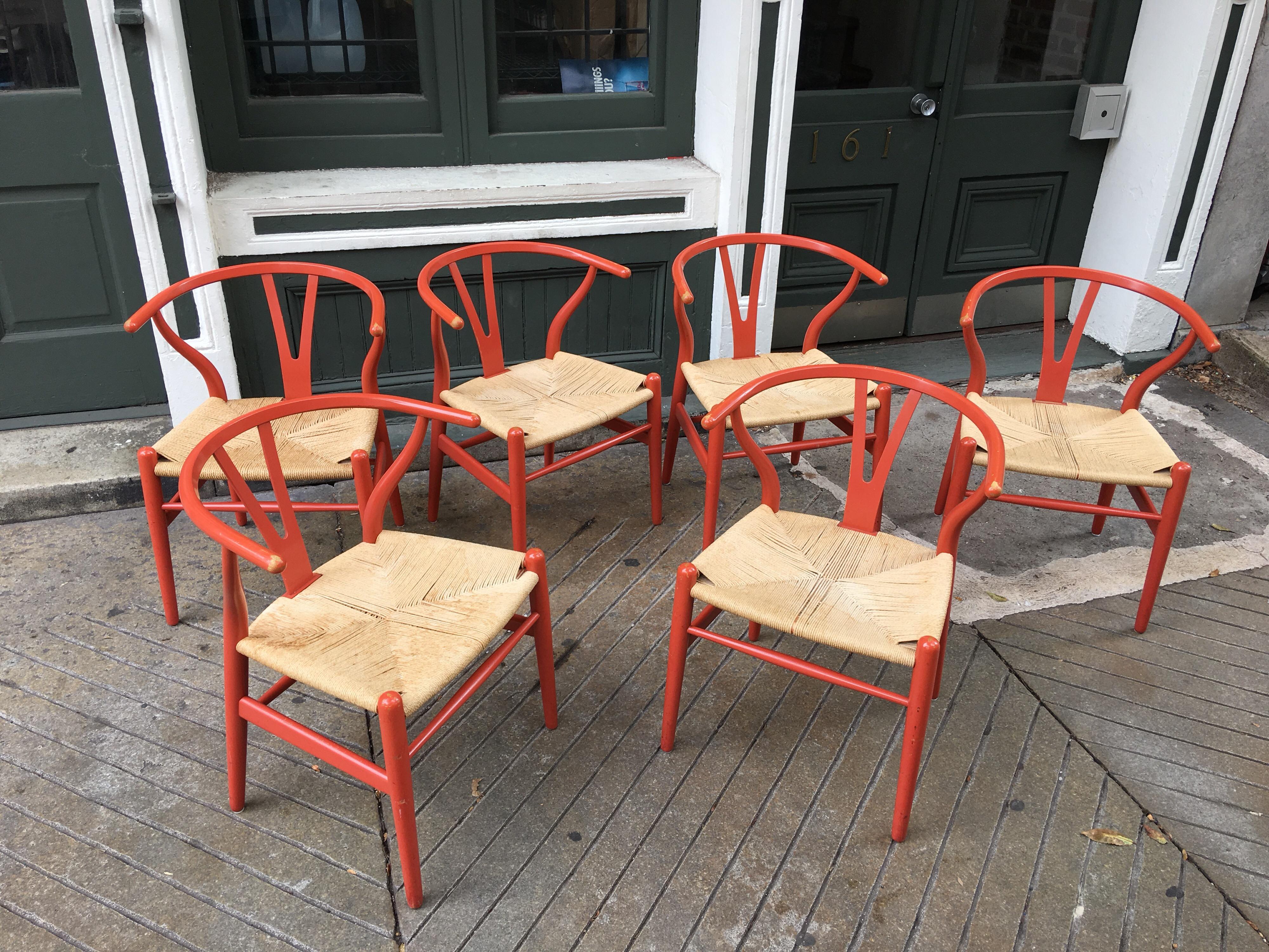 Hans Wegner set of six wishbone chairs in a coral paint. Chairs show patina, and caning has some wear. Couple chairs retain their original decal labels.
 