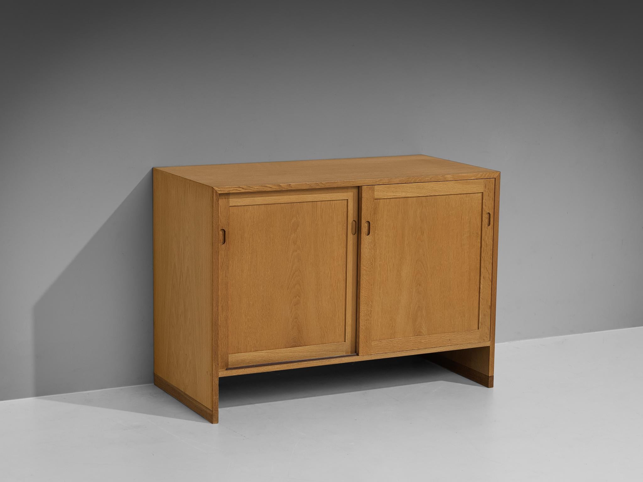 Hans Wegner for Ry Møbler, cabinet, oak, Denmark, 1960s.

This cabinet is executed in oak and is typical for Mid-Century Scandinavian design. It contains two sliding doors which reveals two inner compartments with shelves and offer plenty of