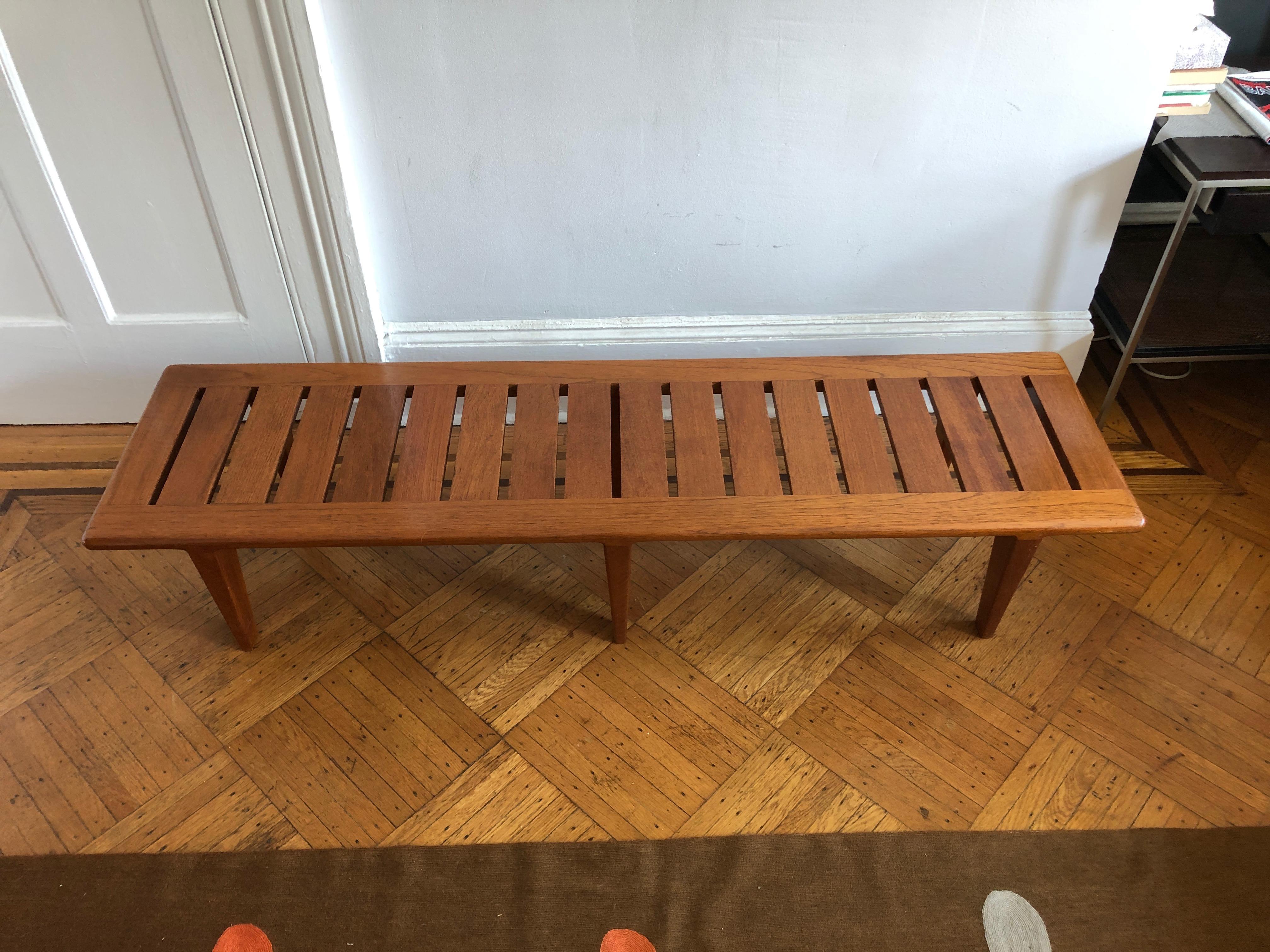 Iconic solid teak bench with slatted wood and tapering legs, stamped underneath Johannes Hansen.