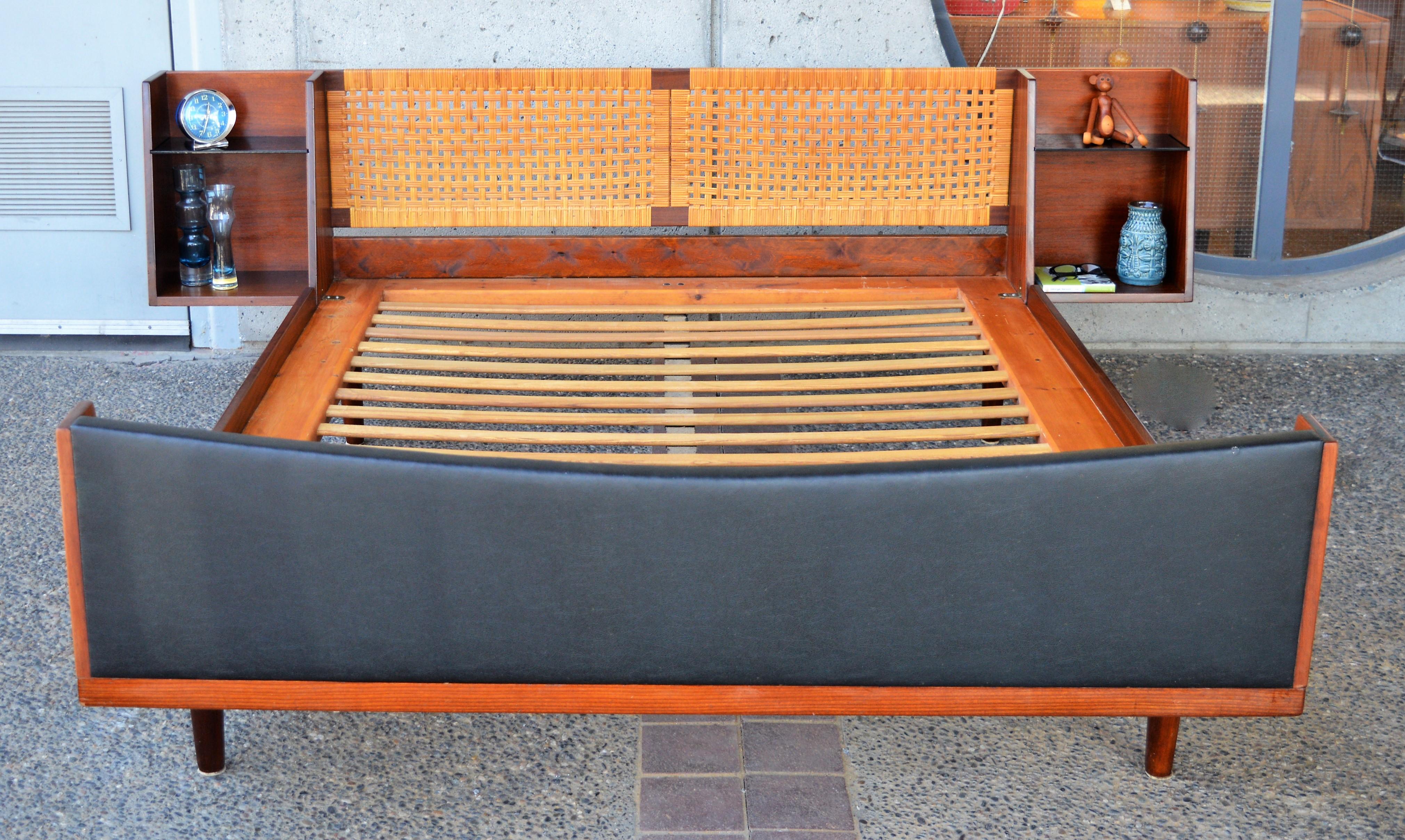 This spectacular and rare Danish modern teak quality bed was designed by Hans Wegner for GETAMA in the 1960s. Featuring a caned headboard with floating bedside tables on either side. The bedside tables taper back towards the top - a feature echoed
