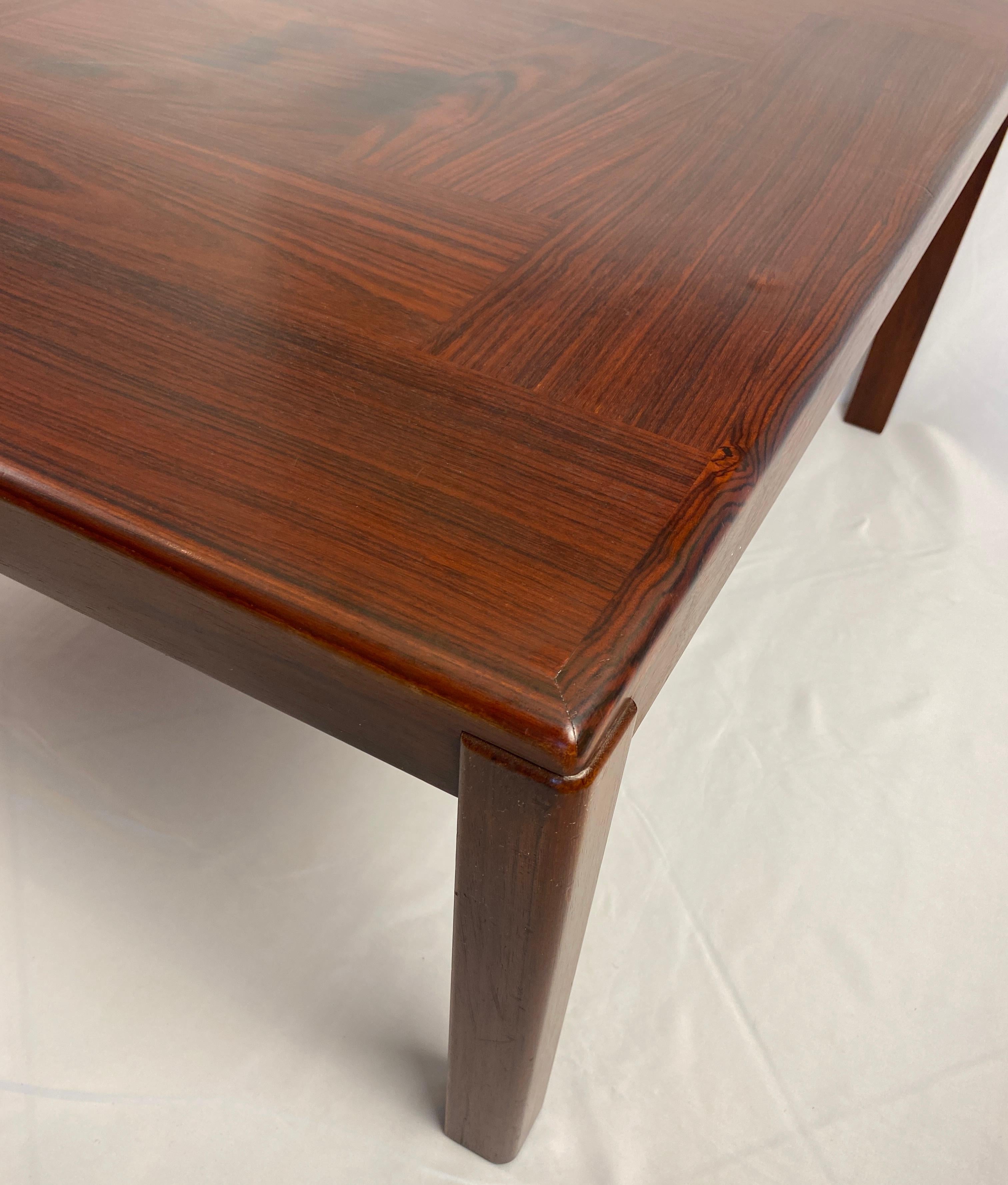 Una mesa de centro de estilo Hans Wegner o mesa de centro danesa muy elegante hecha de madera maciza y chapada de palisandro.  Las líneas limpias y los surcos naturales de la madera realzan el diseño de la preciosa mesa de centro de madera de estilo