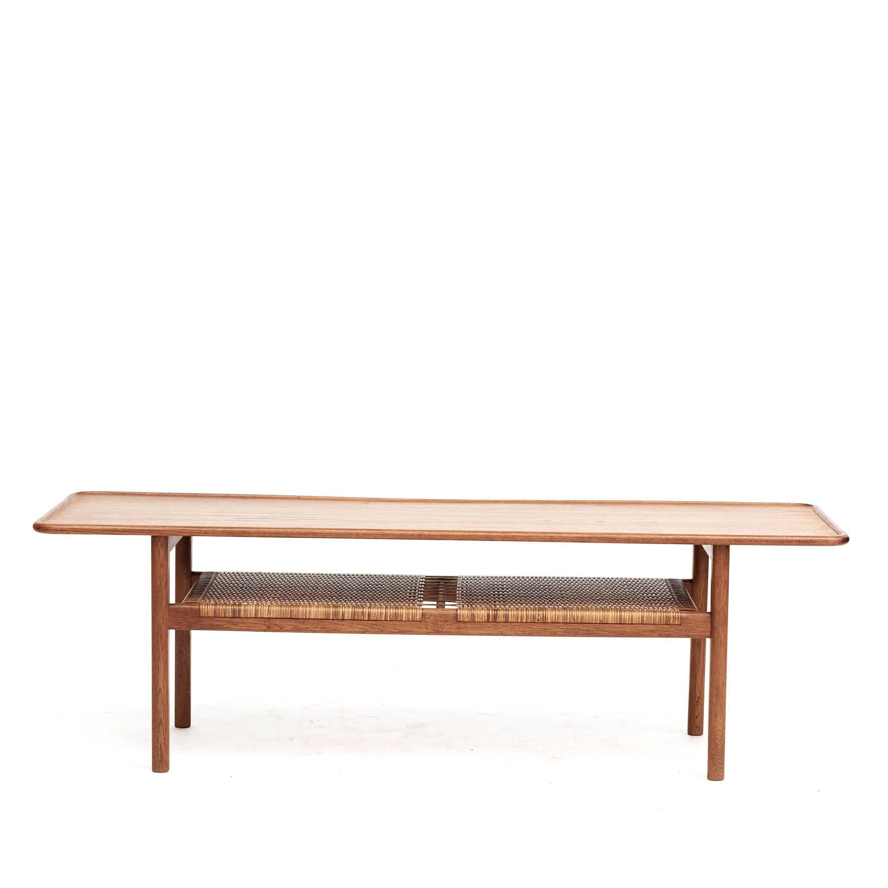 Hans J. Wegner 1914-2007.
Coffee table model AT-10 in solid teak.
Top with raised edge and an underlying woven cane shelf.
Designed in 1953, produced by Andreas Tuck.

Original condition with a new oil finish.
