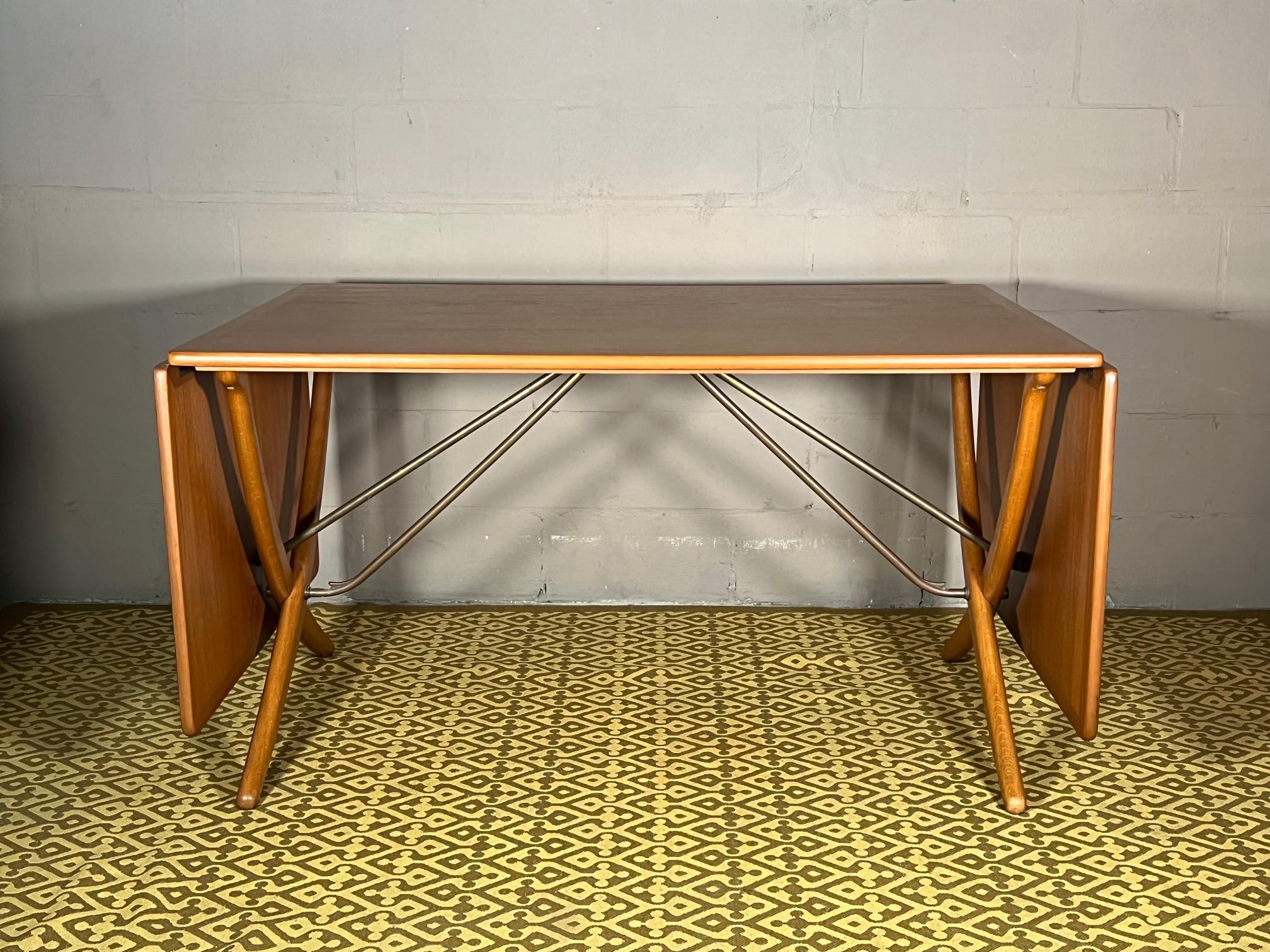 A classic drop leaf dining table by Hans Wegner manufactured by Andreas Tuck, Denmark, ca' 1950's. Top is oak and legs are teak, with original brass pop up mechanism that is such a trademark feature of this design. When opened measures 28