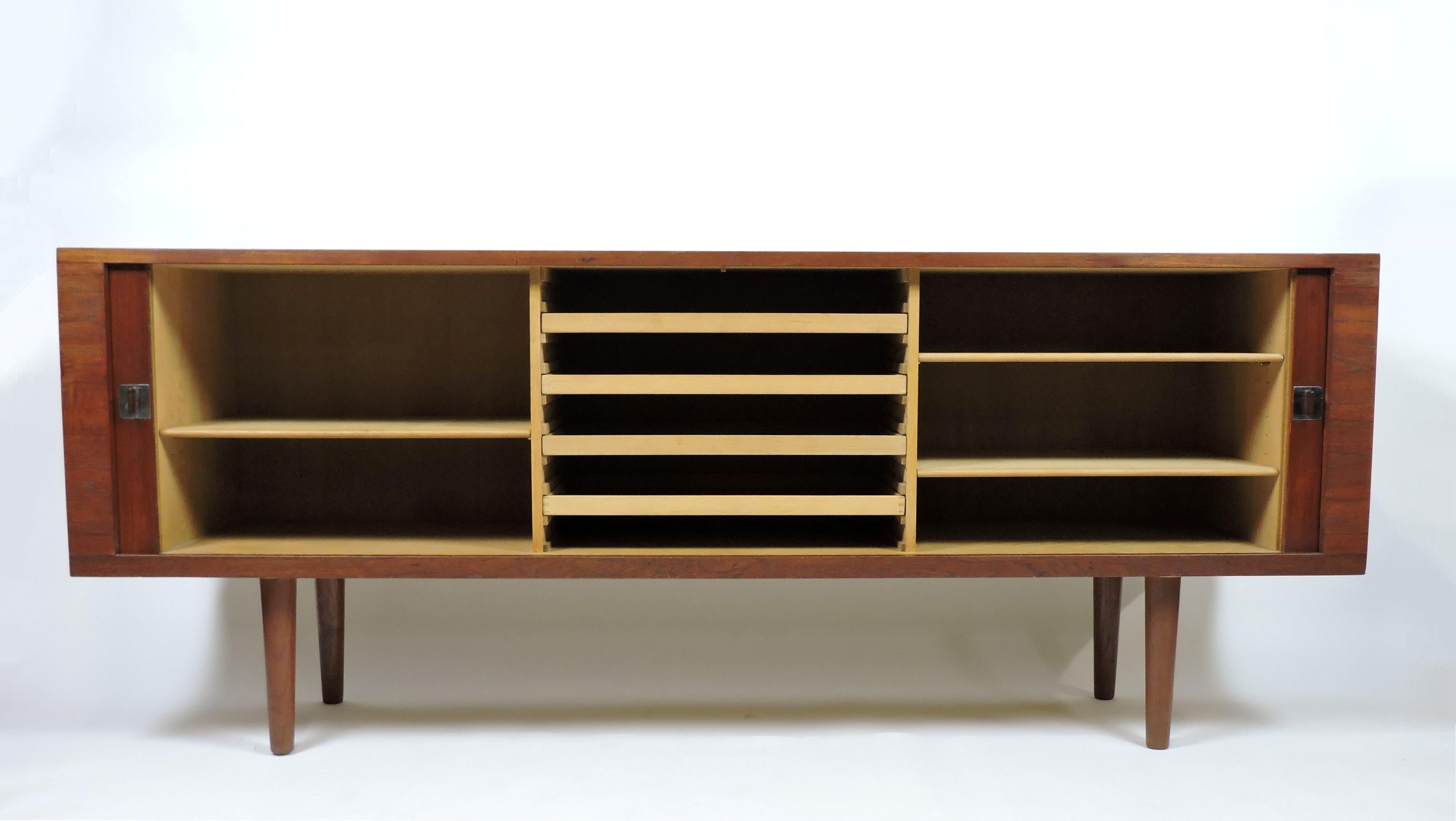 Elegant President credenza in teak designed by Hans Wegner and manufactured in Denmark by Ry Mobler. This handsome credenza has smooth sliding tambour doors with chrome and teak pulls, and rests on tapered teak legs. The oak interior has five