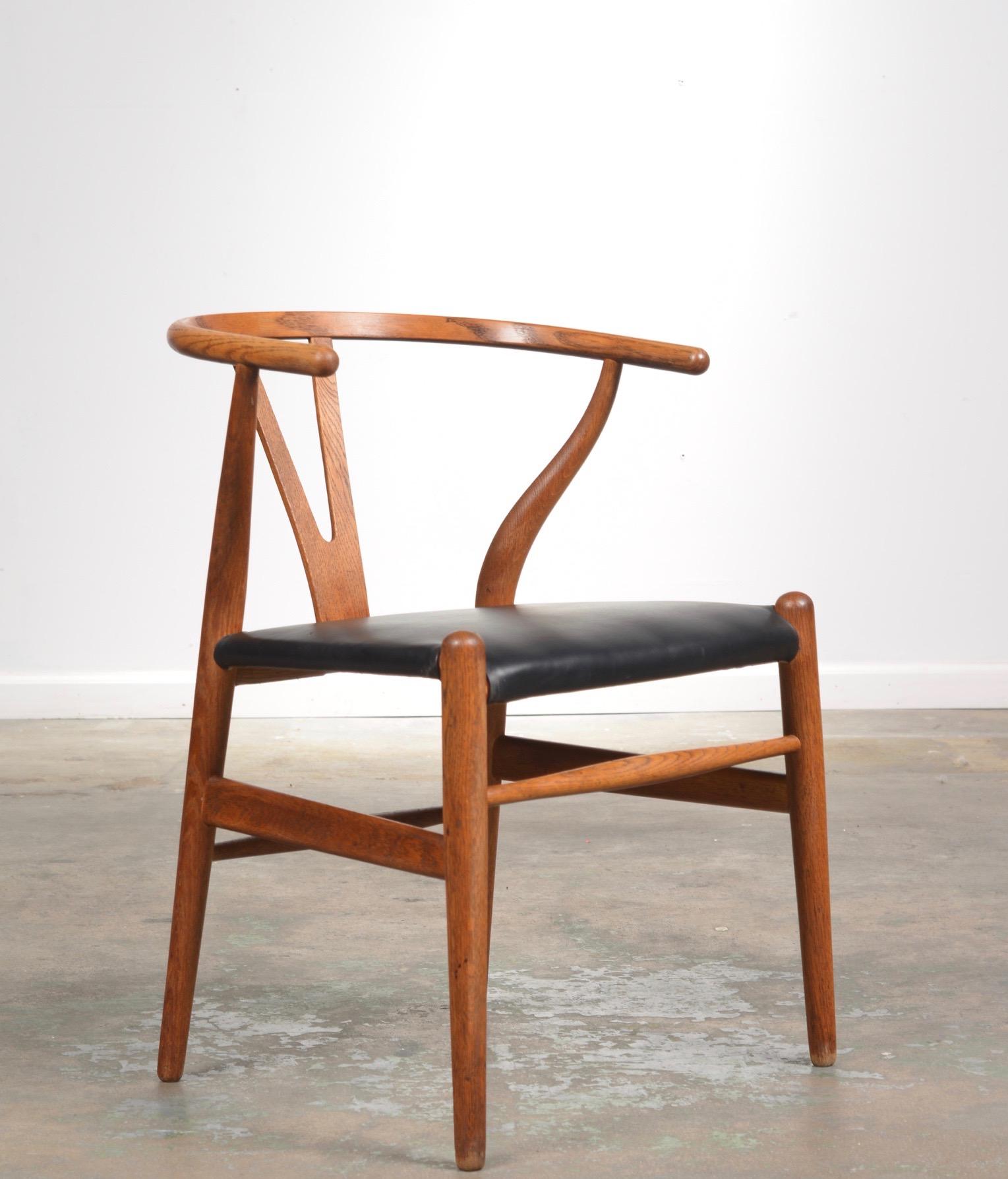 Oiled Oak frame with black leather seat 1st generation Hans Wegner Wishbone chair. A simple, light and appealing shape, this is the most sold chair produced by Carl Hansen and Søn.