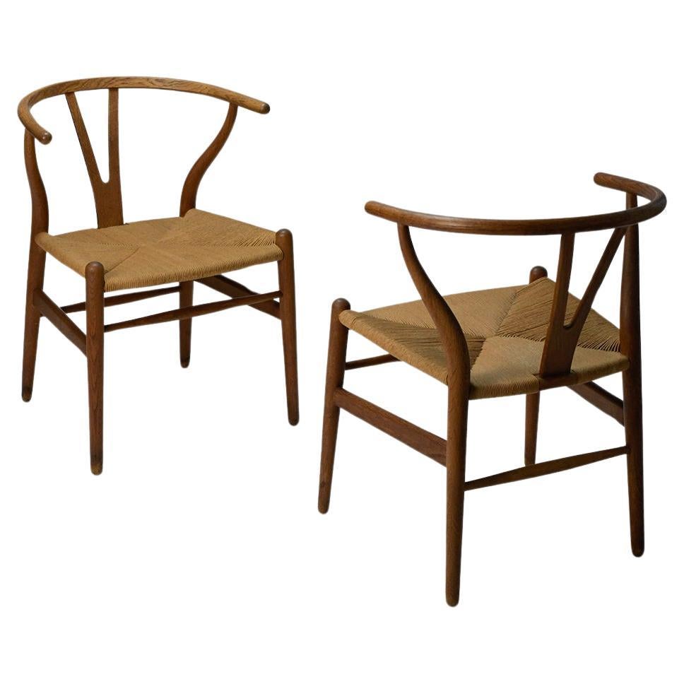 Paire de chaises Wishbone de Hans J. Wegner par Carl Hansen & Son. 

Nous ne sommes pas certains de la date de fabrication de ces chaises, mais nous pensons qu'elles ont été produites dans les années 1960. Compte tenu de leur âge, ils sont en très