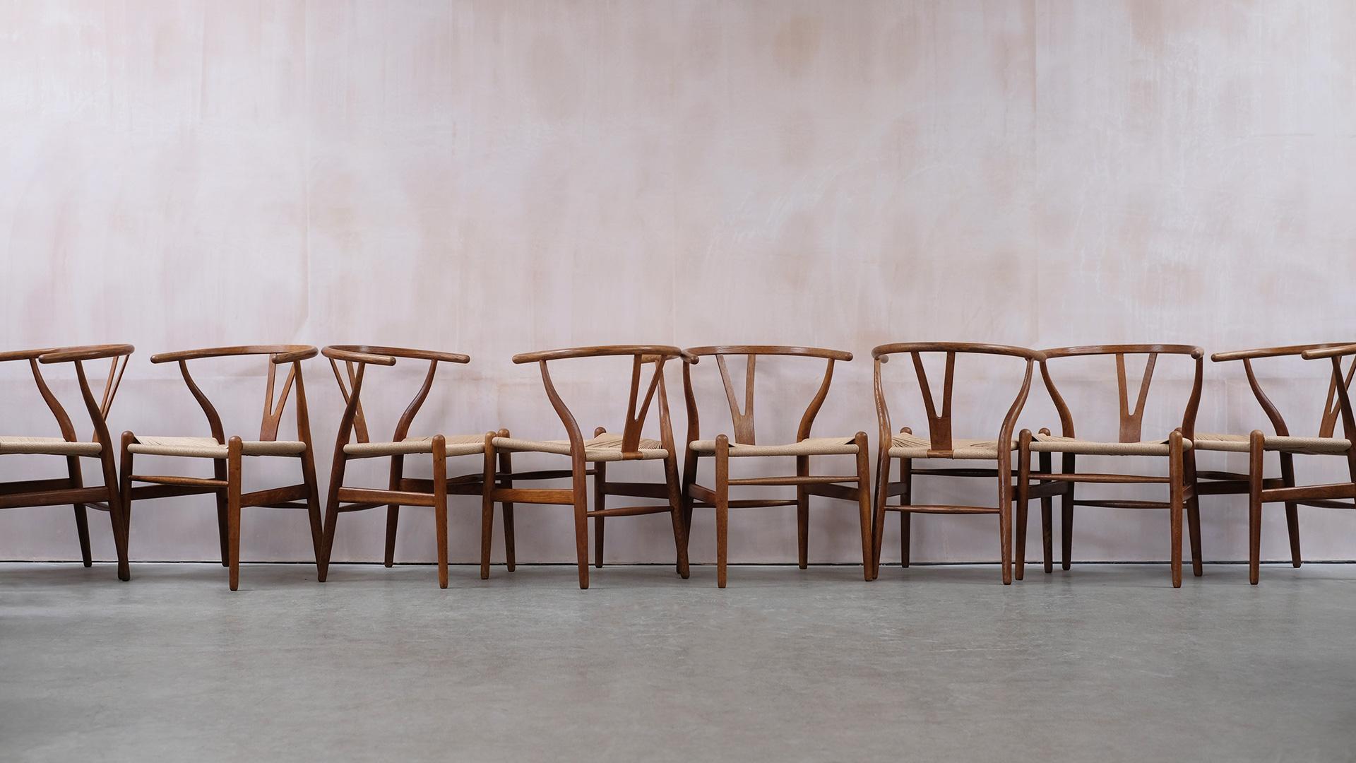 Amazing large set of 8 Classic Wishbone chairs designed by Hans Wegner for Carl Hansen, Denmark. Superb condition with wonderful dark patina to the oak and all redone with new paper cord seats. Fantastic set.