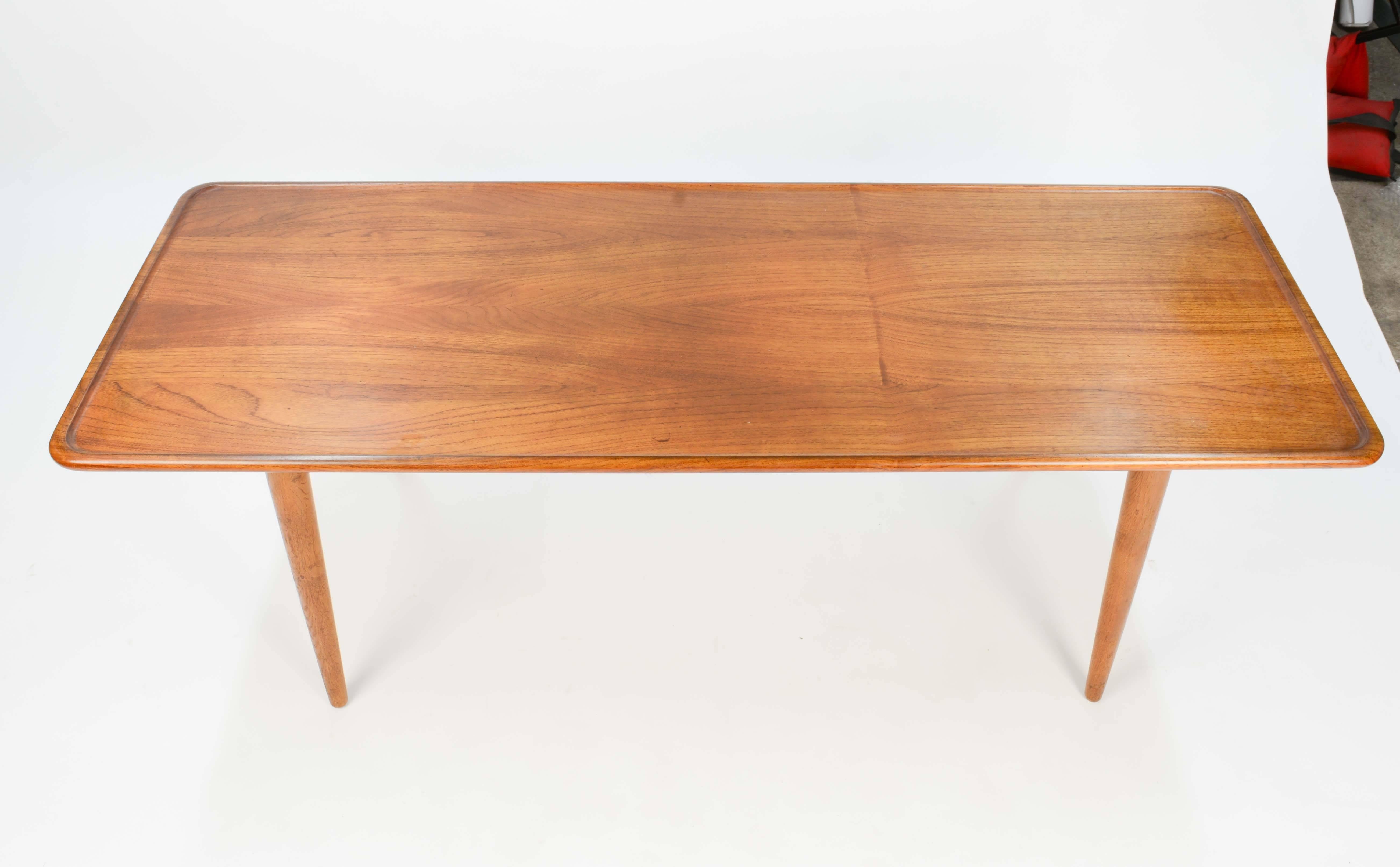Hans Wegner designed coffee table for Andreas Tuck of Denmark. Having a sculpted teak lip top on oak legs. Table has finely detailed wood craftmanship and graining. It is branded with the Tuck label and Wegner name.