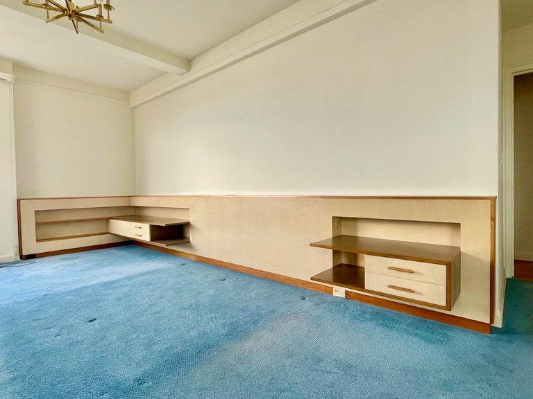 Custom L shaped headboard cabinet wall with floating nightstands and bookshelves designed by Hans Weiss in 1960 for the master bedroom of an Upper West Side apartment.
Top of 'wall' inset with florescent lights with opaque glass panel reflectors.
