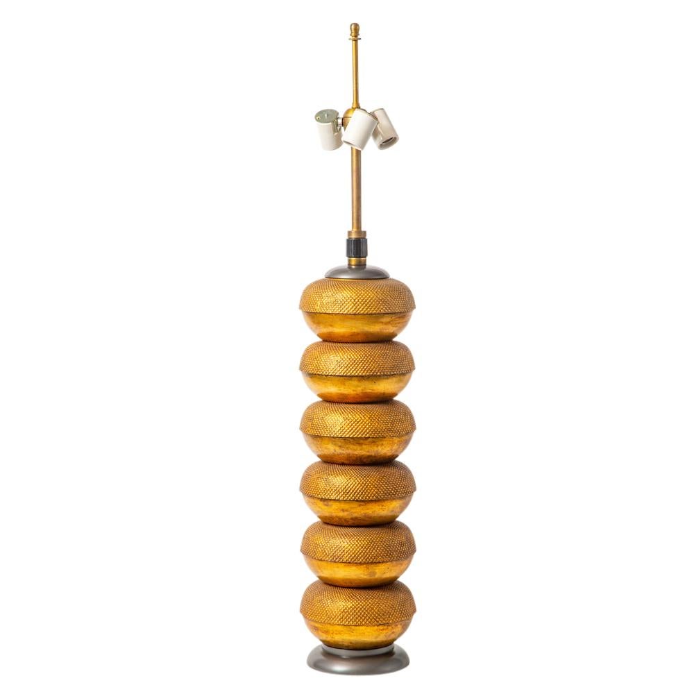 Hansen lamp, textured gilt metal and painted wood. Tall table lamp composed of six stacked bronze toned white metal castings and decorated with both a smooth and textured surface. Patented 3-way switch on the post with porcelain sockets. In nice