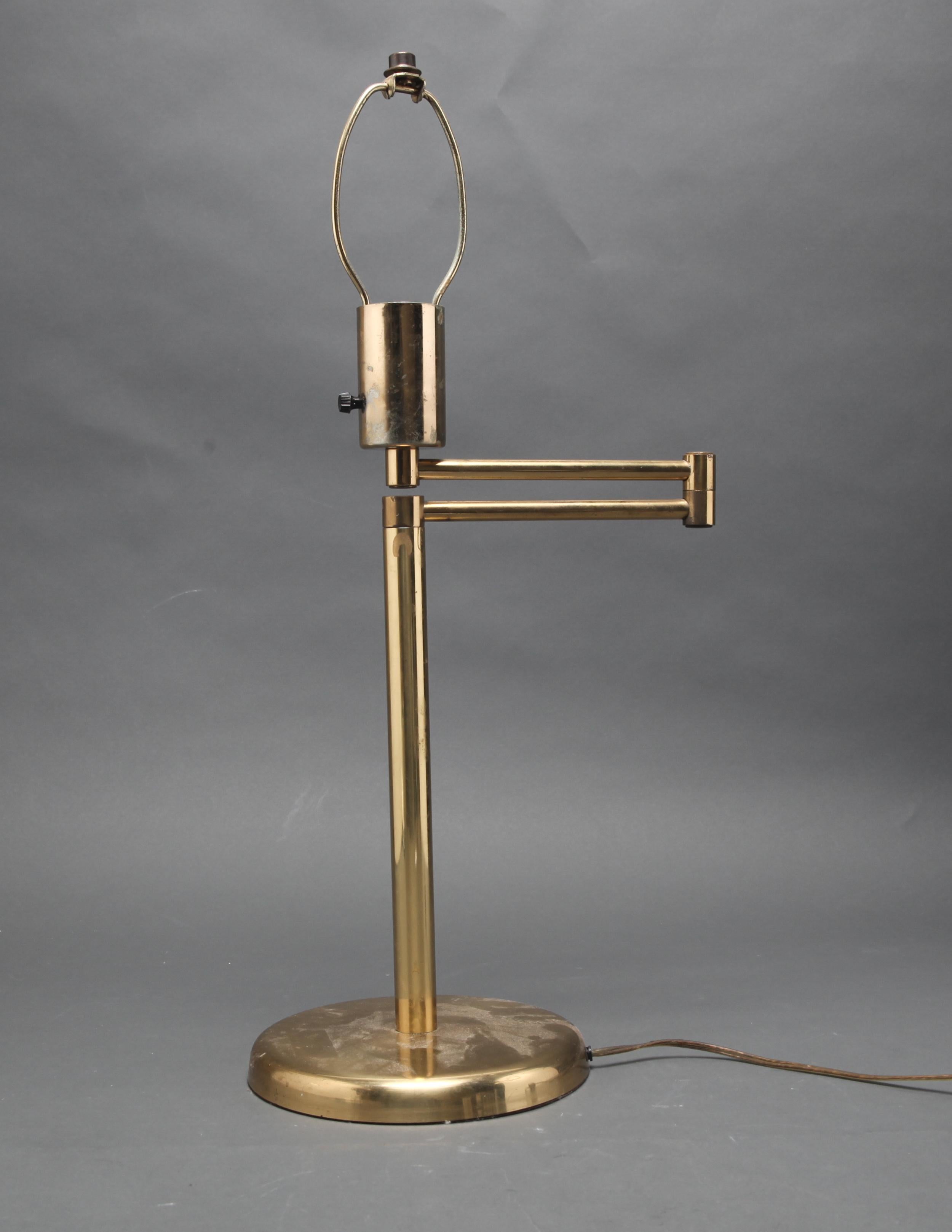 Mid-Century Modern brass table lamp with adjustable swing arm designed by George Hansen, with a round base. The piece is in great vintage condition with age-appropriate wear.