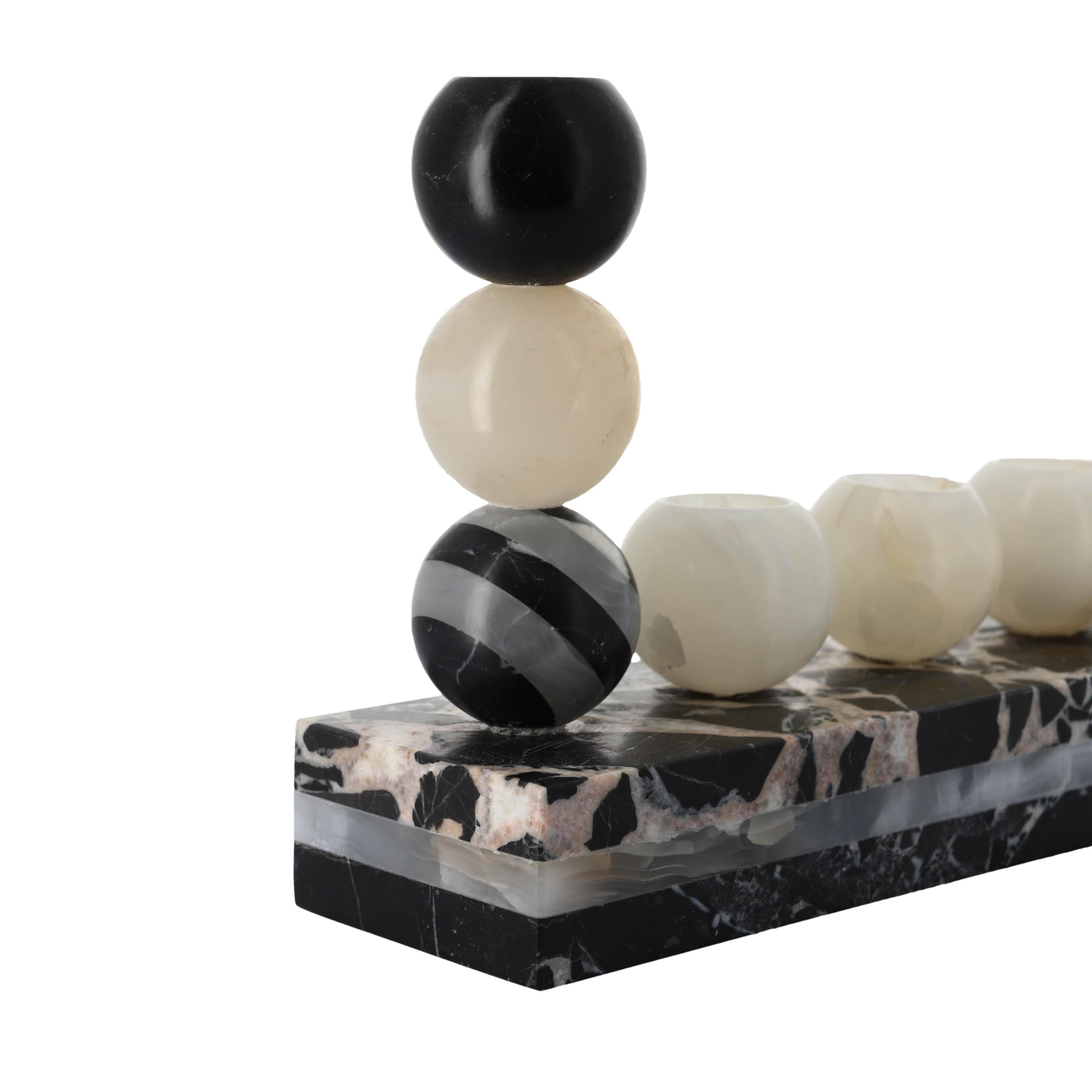 This striking Hanukkiah by Studio Gaïa embodies the poetry of contrast — carved from Grand Antique marble and White Onyx, it reinterprets the ritual of Hanukkah with sculptural precision and quiet strength.

Each of the nine spheres is hand-sculpted