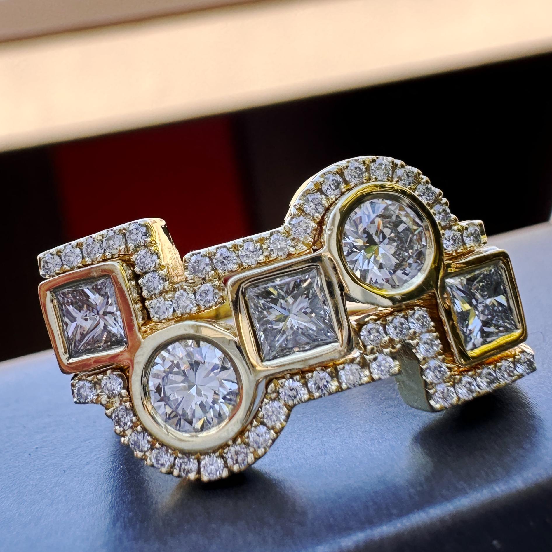 Siamo orgogliosi di presentare un audace e modernista set di tre anelli di Eytan Brandes.  L'anello centrale presenta cinque diamanti rotondi e quadrati in una linea disordinata.  Al di sopra e al di sotto di esso ci sono sottili fasce che tracciano