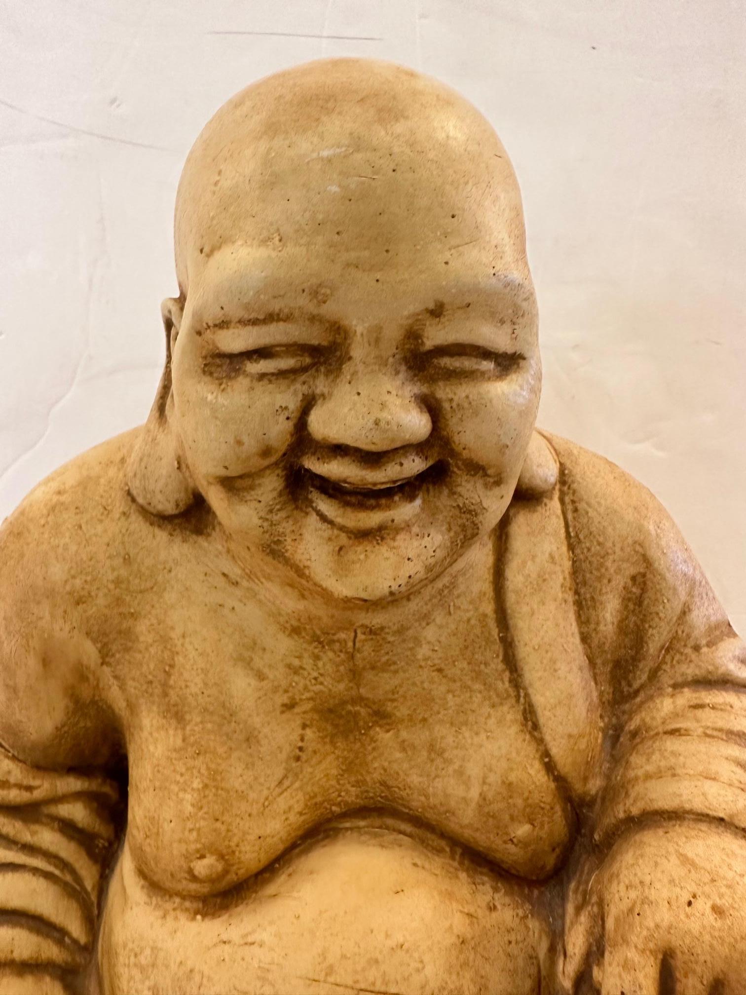Irrésistible sculpture de Bouddha assis en pierre moulée, à l'expression joviale et aux détails soignés.