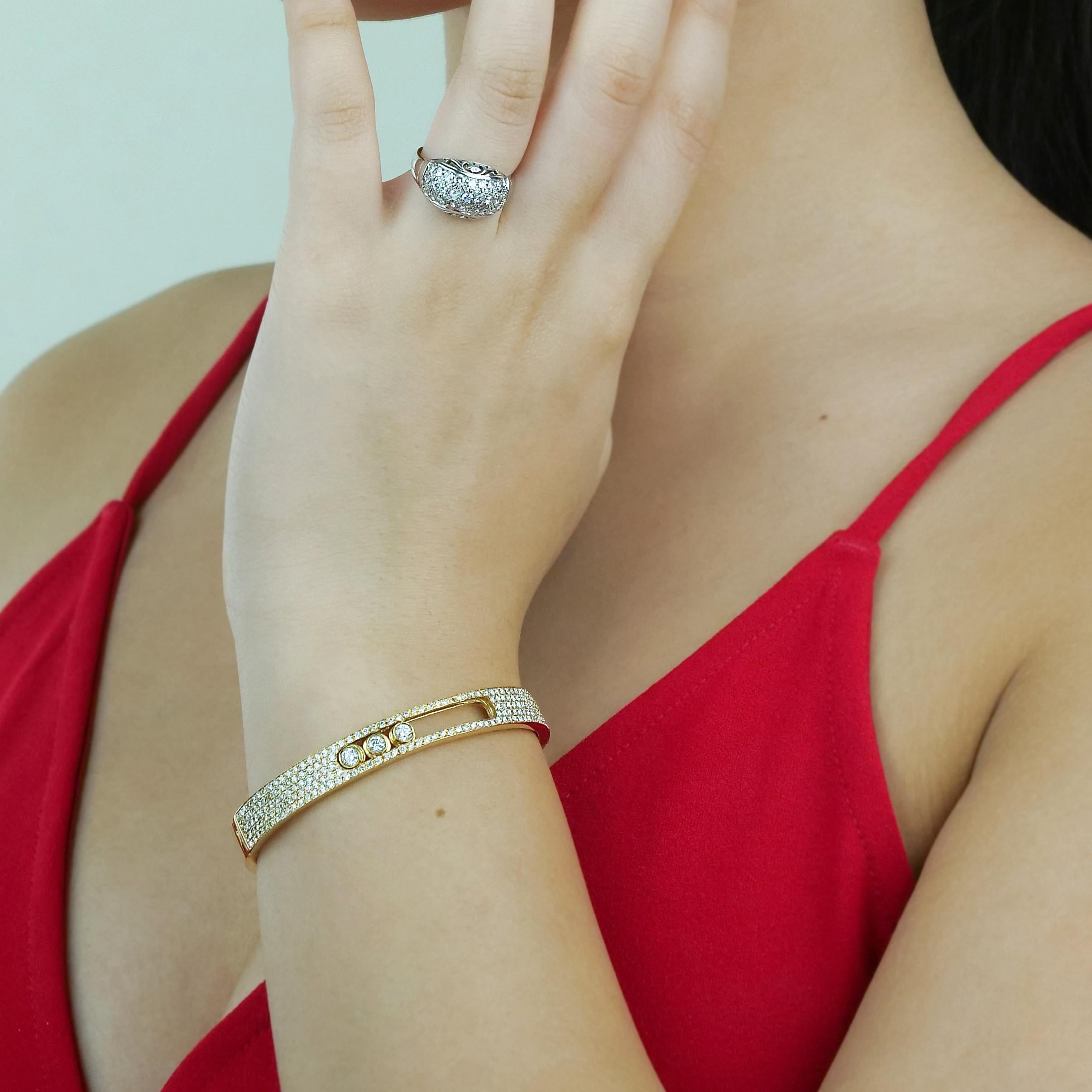 This dynamic bangle consists of three moving diamond centers, held in a frame of smaller diamonds. Set in 18ct yellow gold, it compliments with warmth, the cool white glittering brilliant cut diamonds for a beautiful and unique design.

Round